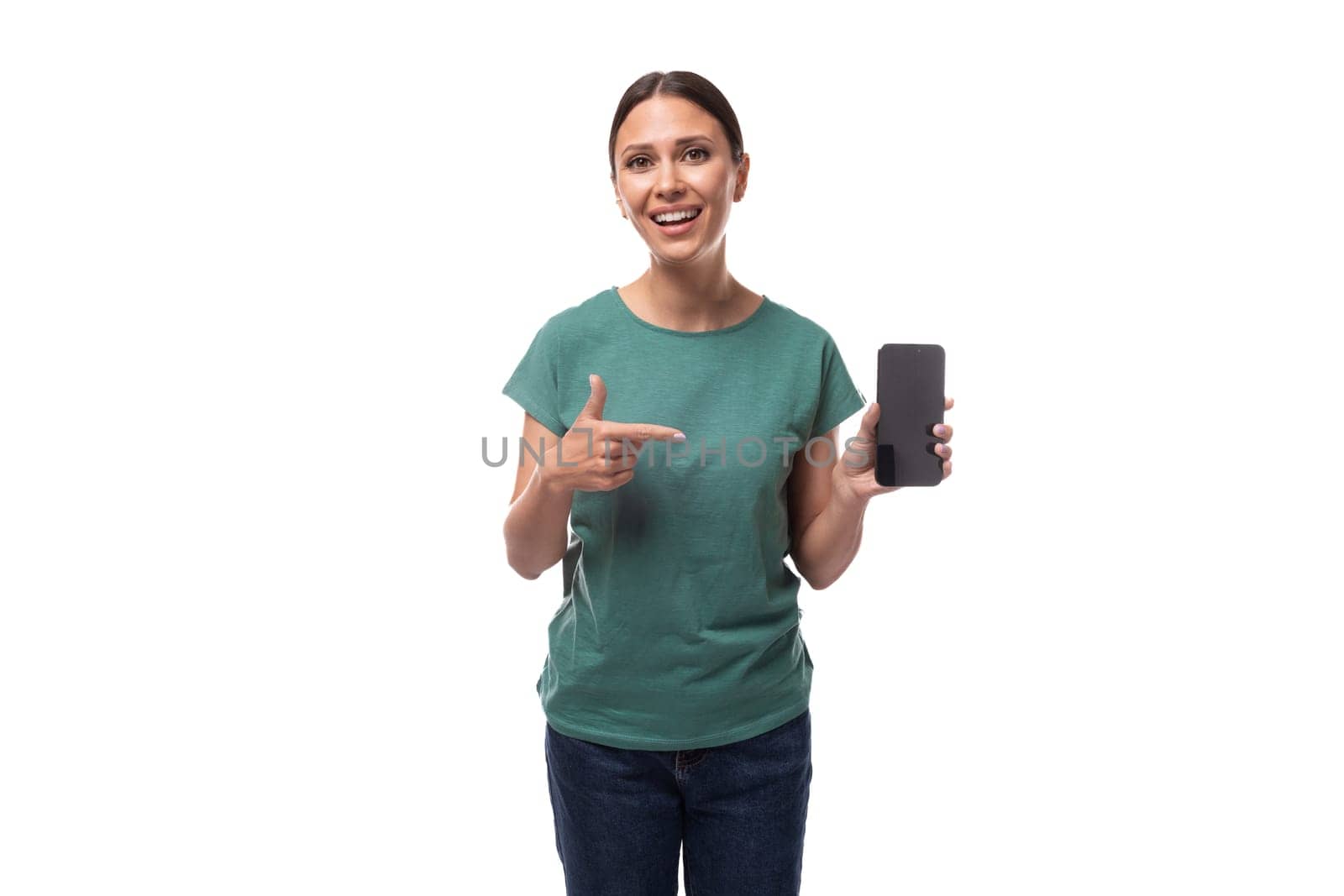 young energetic slender european woman with a ponytail hairstyle dressed in a green t-shirt holds a smartphone.