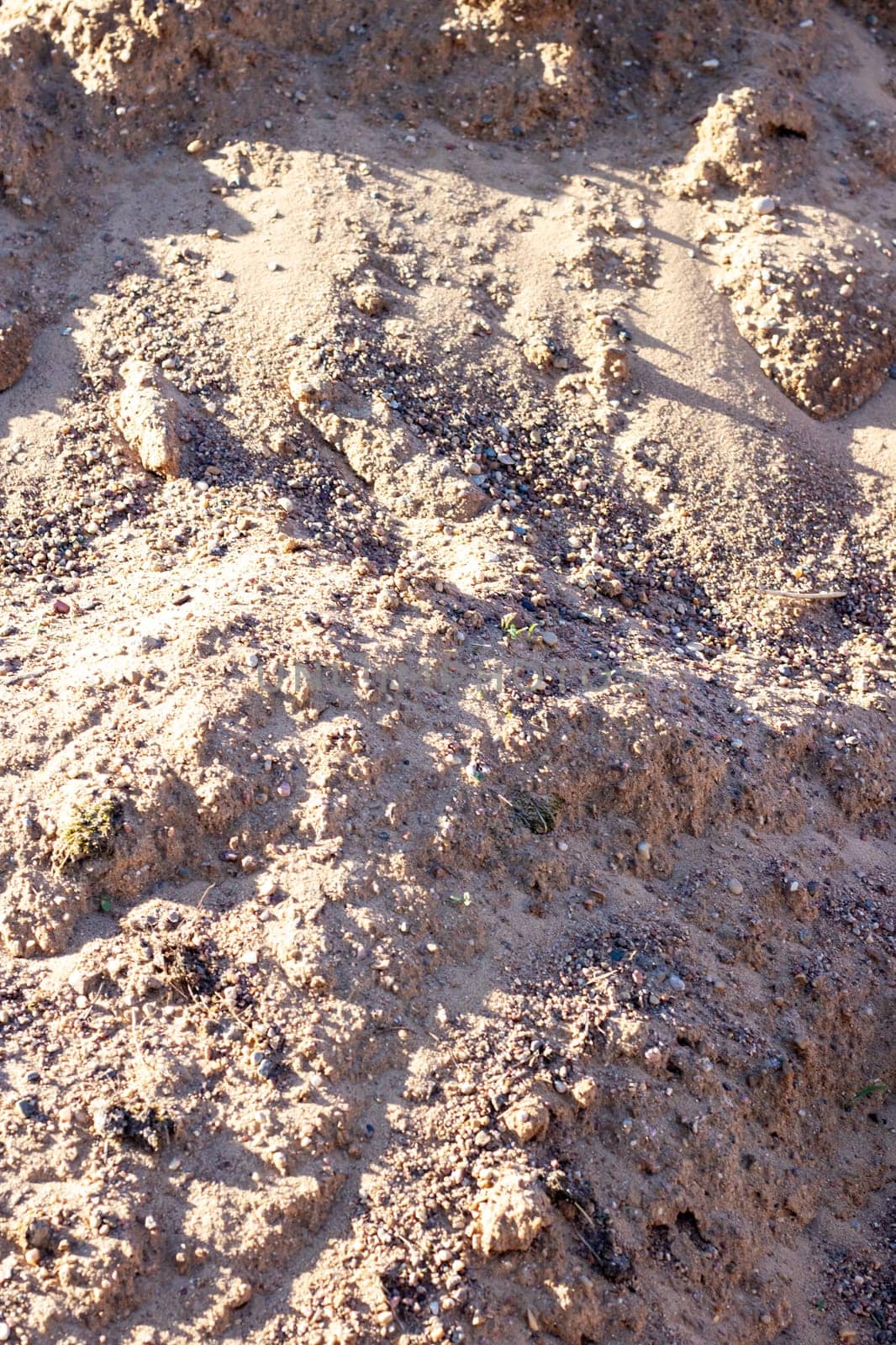 A mixture of soil, brown bedrock, and small rocks resembling a mini landscape. The pattern of rocks creates an interesting contrast in the grassy area, similar to a road surface with asphalt