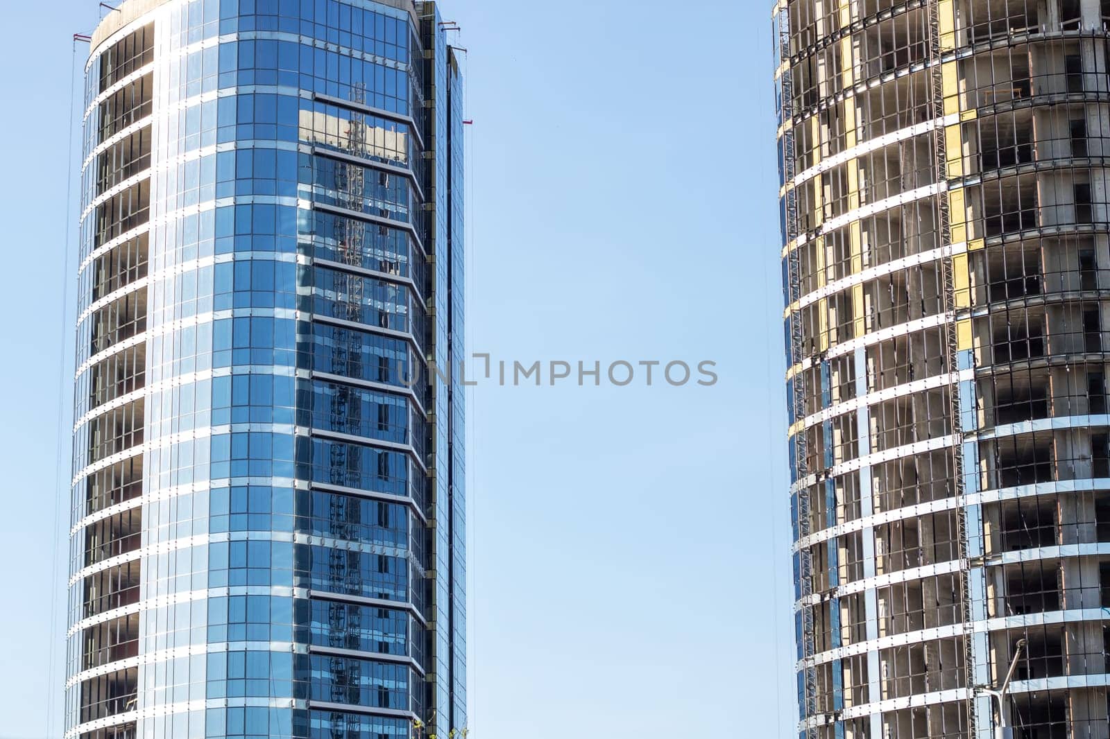 A modern skyscraper with a sleek facade stands tall against the backdrop of a clear blue sky, showcasing urban design and commercial real estate prowess