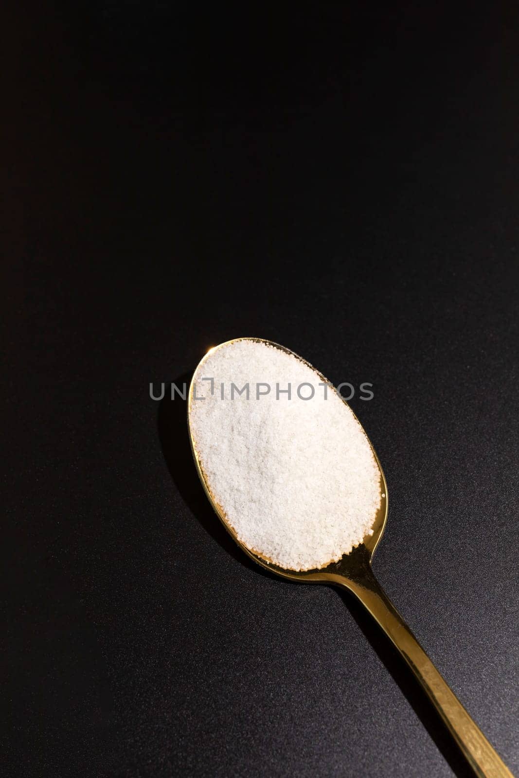 Design Celtic Gray Sea Salt In Golden Spoon on Dark Table, Vertical Plane. Copy Space. Natural, Unrefined Salt Harvested From Brittany, France. Natural Mineral And Trace Elements, Superfood. Seasoning by netatsi