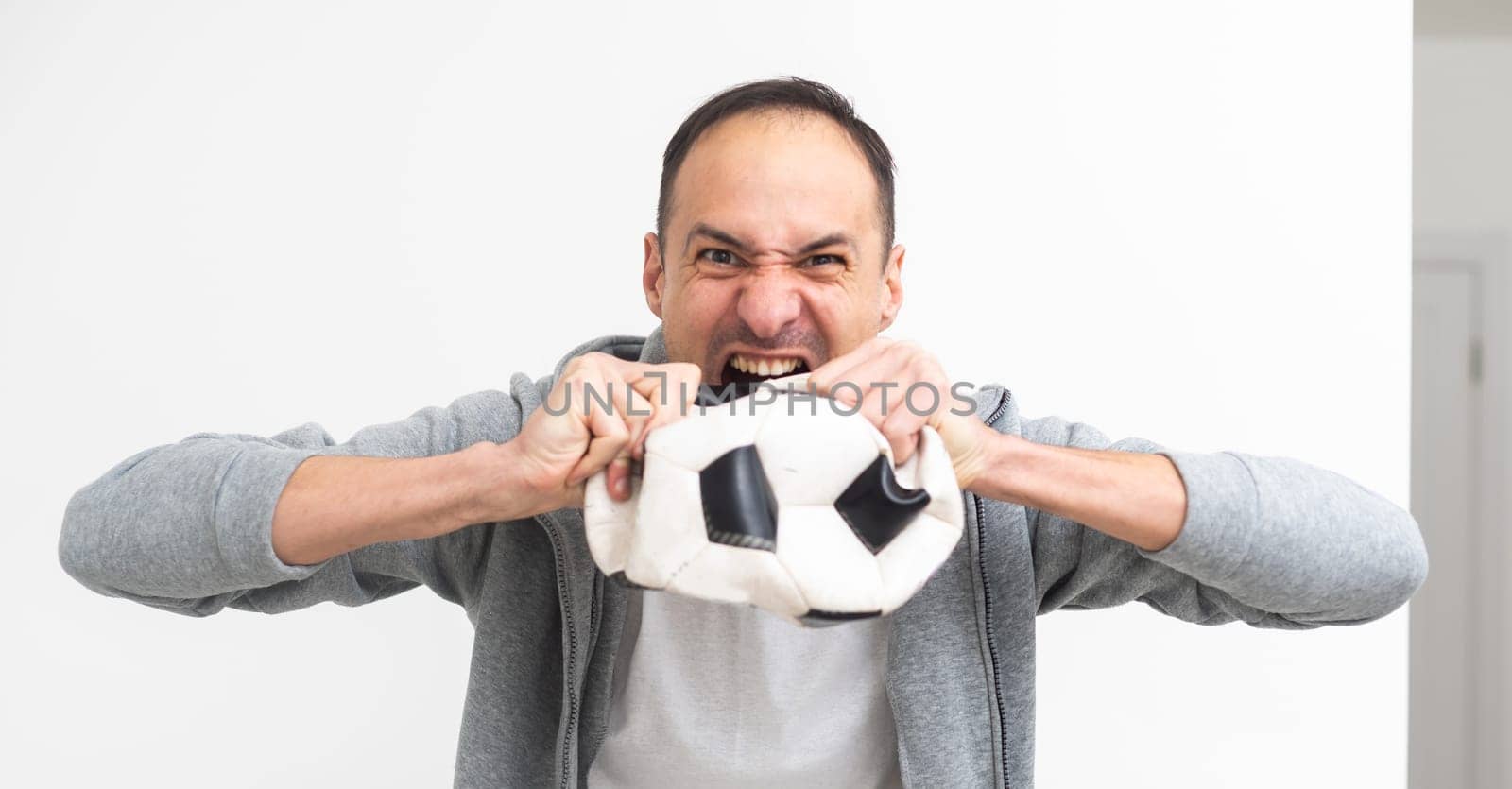Joyful happy young man in shirt posing background. People sincere emotions lifestyle concept. Mock up copy space. Holding soccer ball doing winner gesture screaming by Andelov13