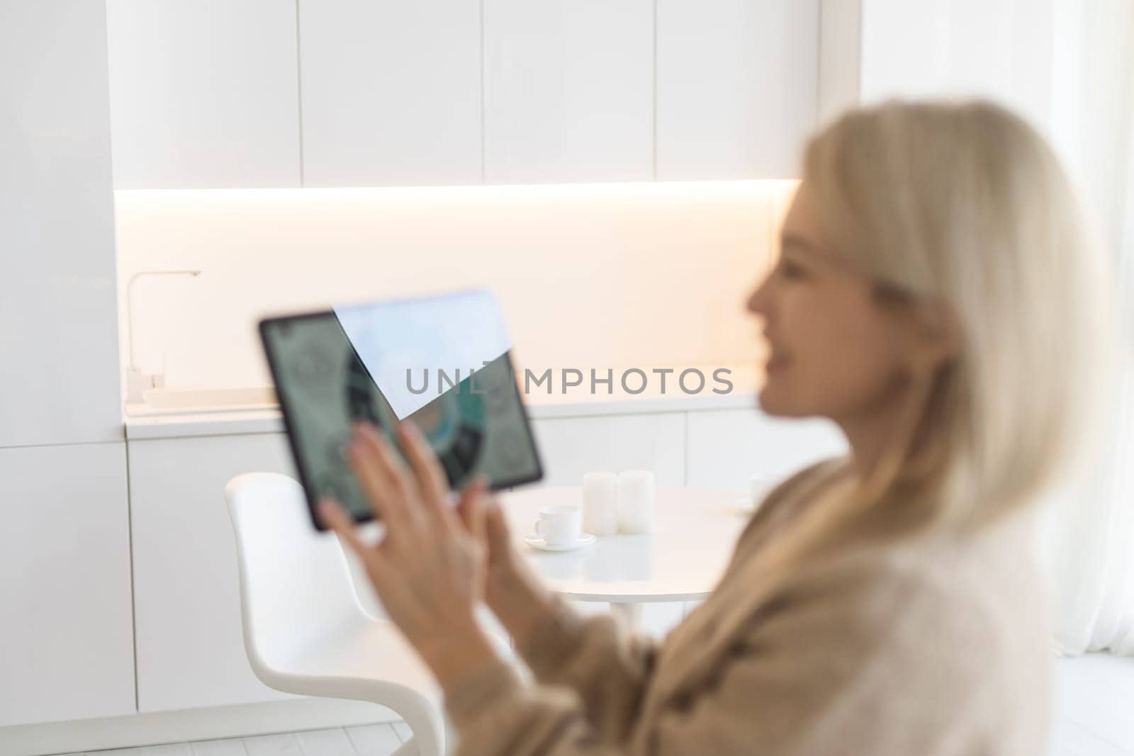 Woman controlling smart home devices using a digital tablet with launched application in the white living room. Smart home concept.