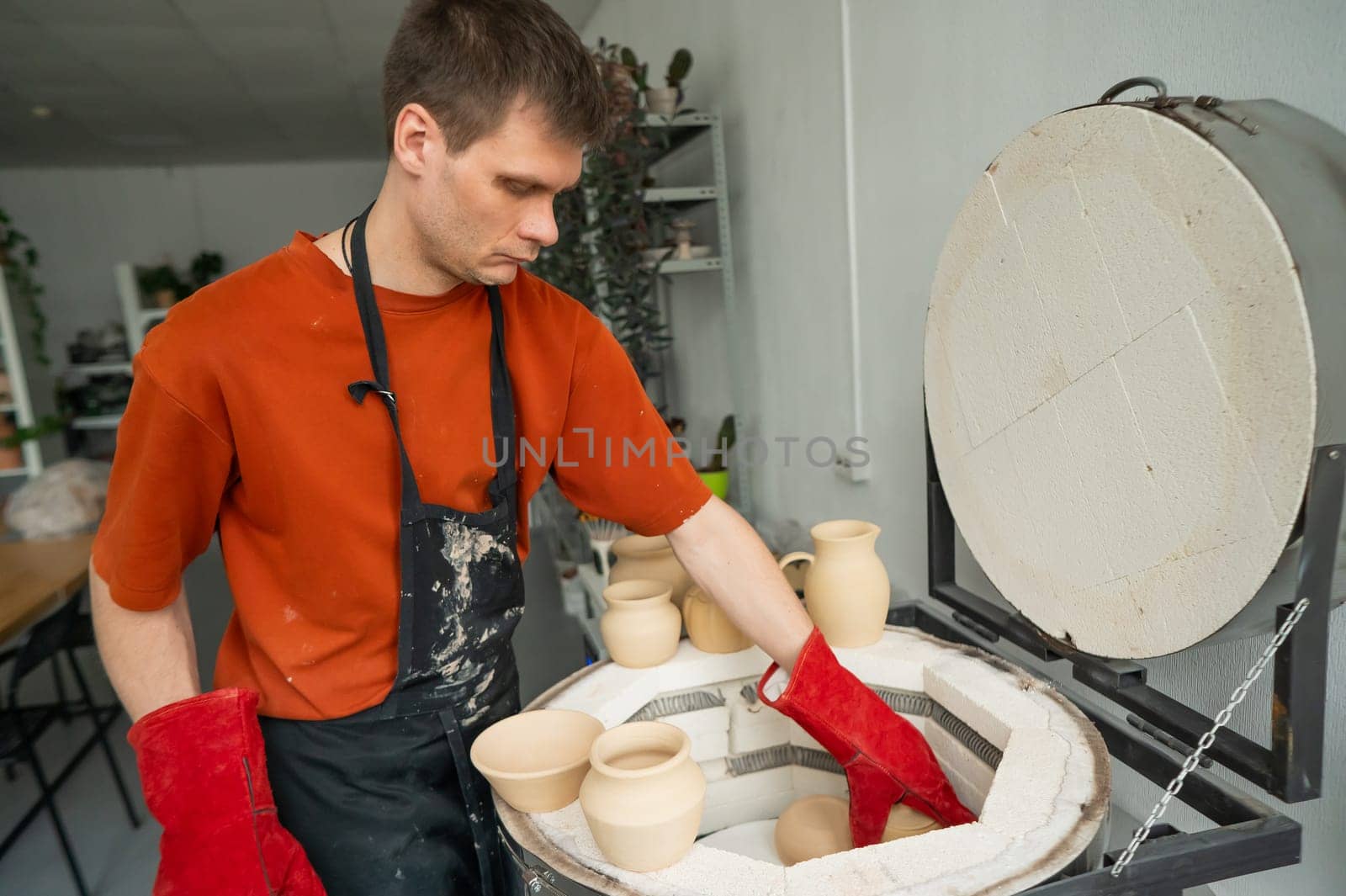 Caucasian man loading ceramic products into a special kiln. by mrwed54