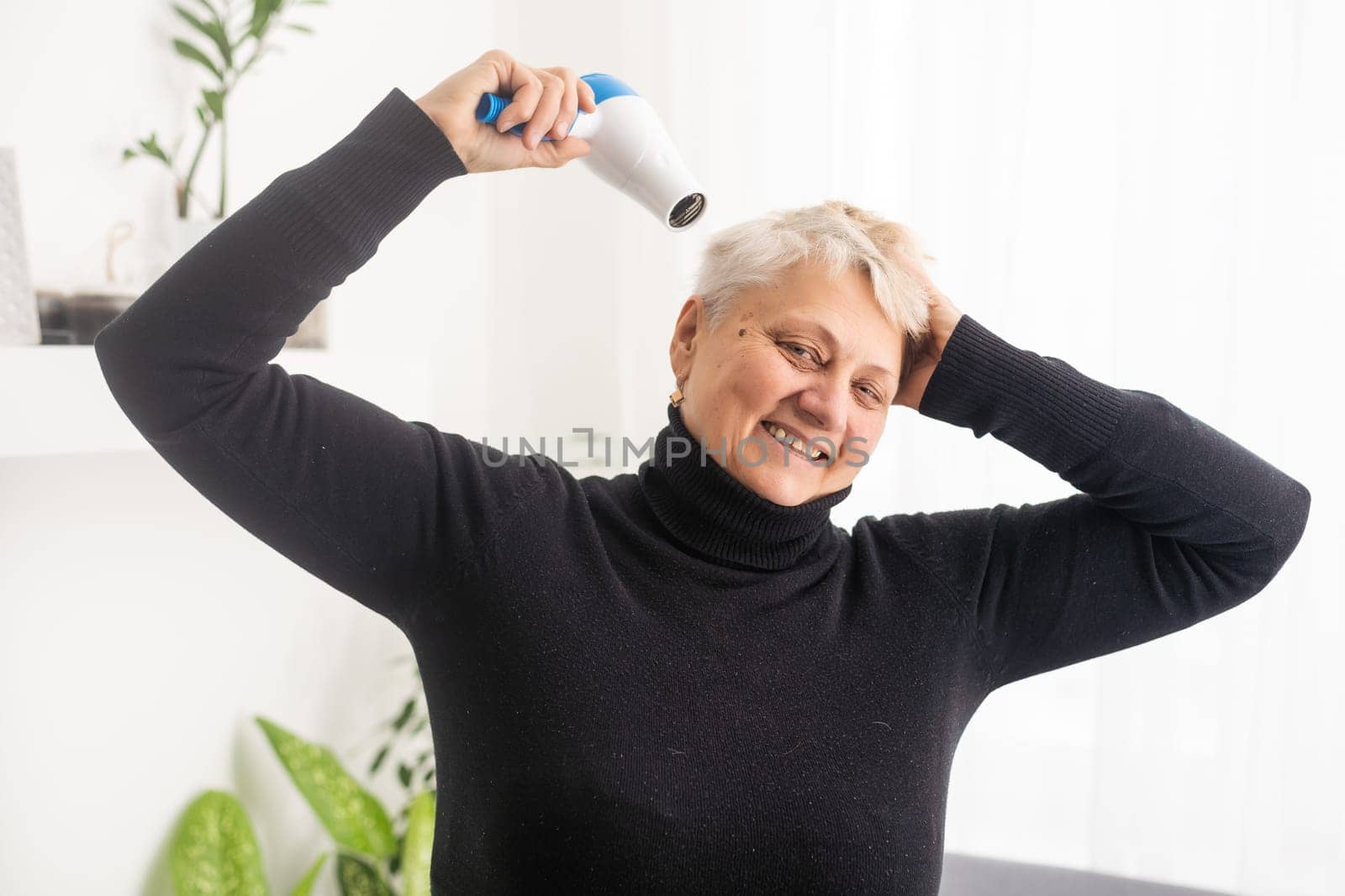 Portrait of senior woman with hair dryer.