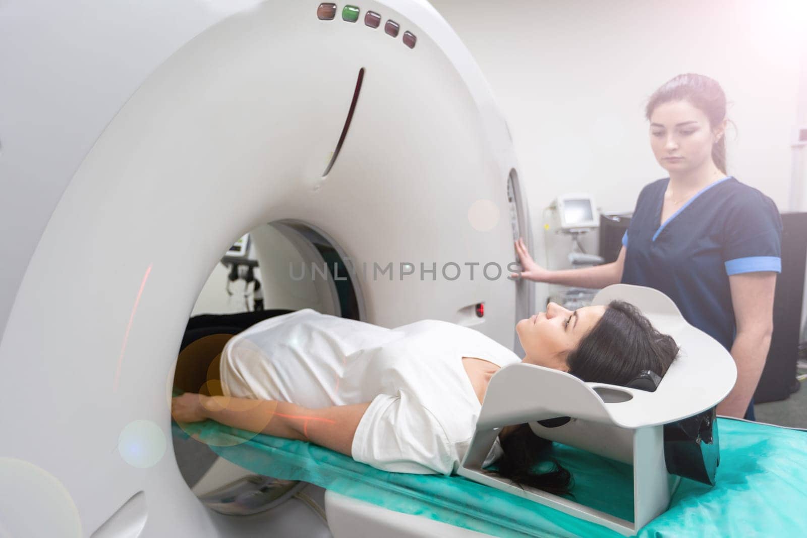 A woman lies on the tomograph table. woman is undergoing computed axial tomography examination in a modern hospital by Andelov13