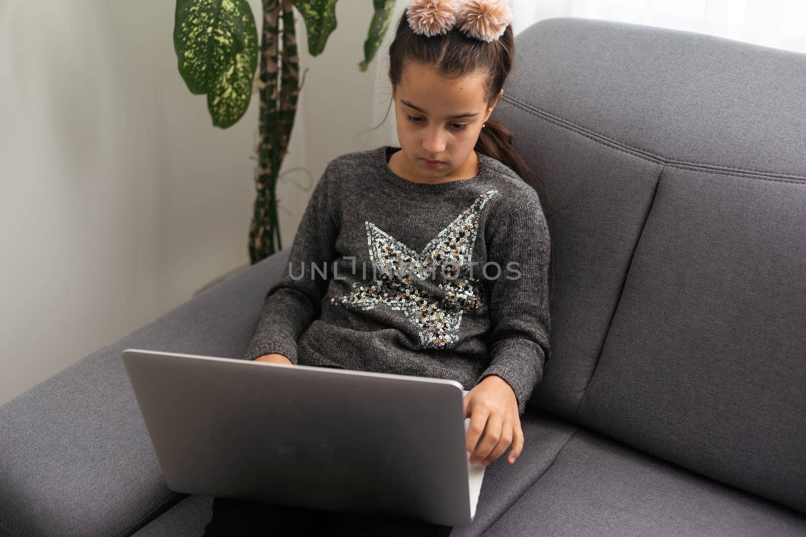 Teen girl school pupil studying online from home making notes. Teenage student distance learning on laptop doing homework, watching listening video lesson. Remote education concept.