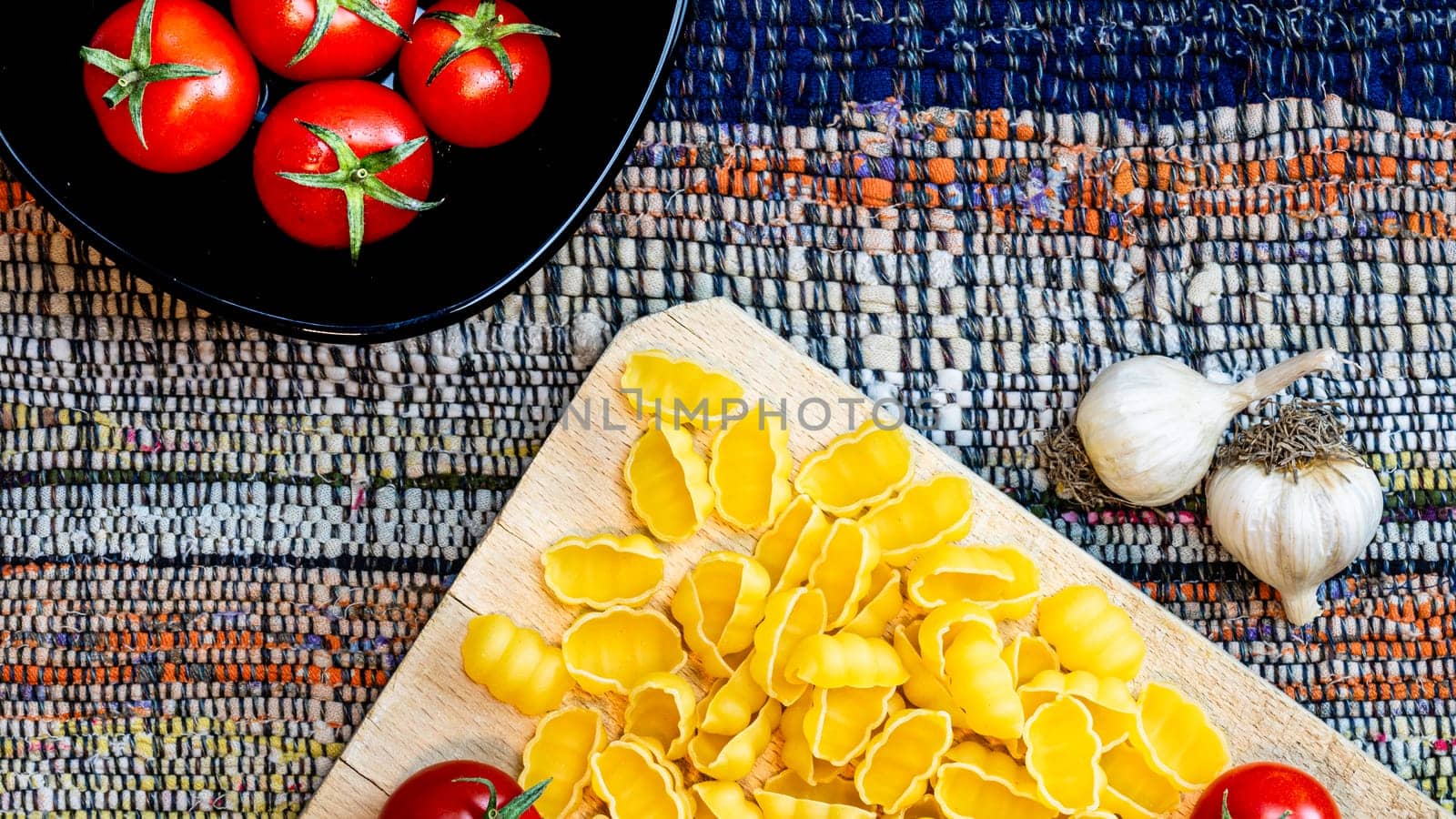 Top detail view of onions and fresh ripe cherry tomatoes in a black bowl on a rustic napkin. Ingredients and food concept