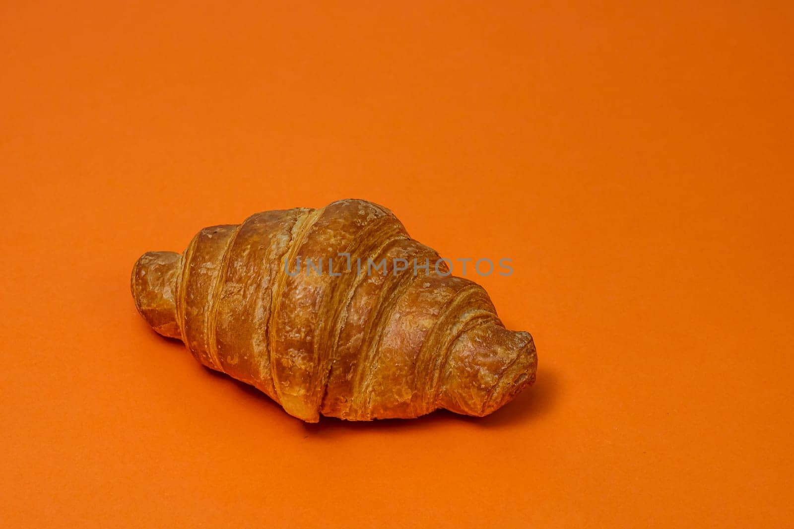  Fresh croissant isolated on orange board. French breakfast concept. by vladispas