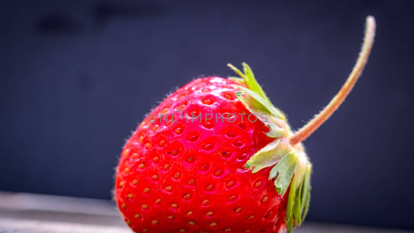 Close up of one strawberry on wooden board isolated on black background