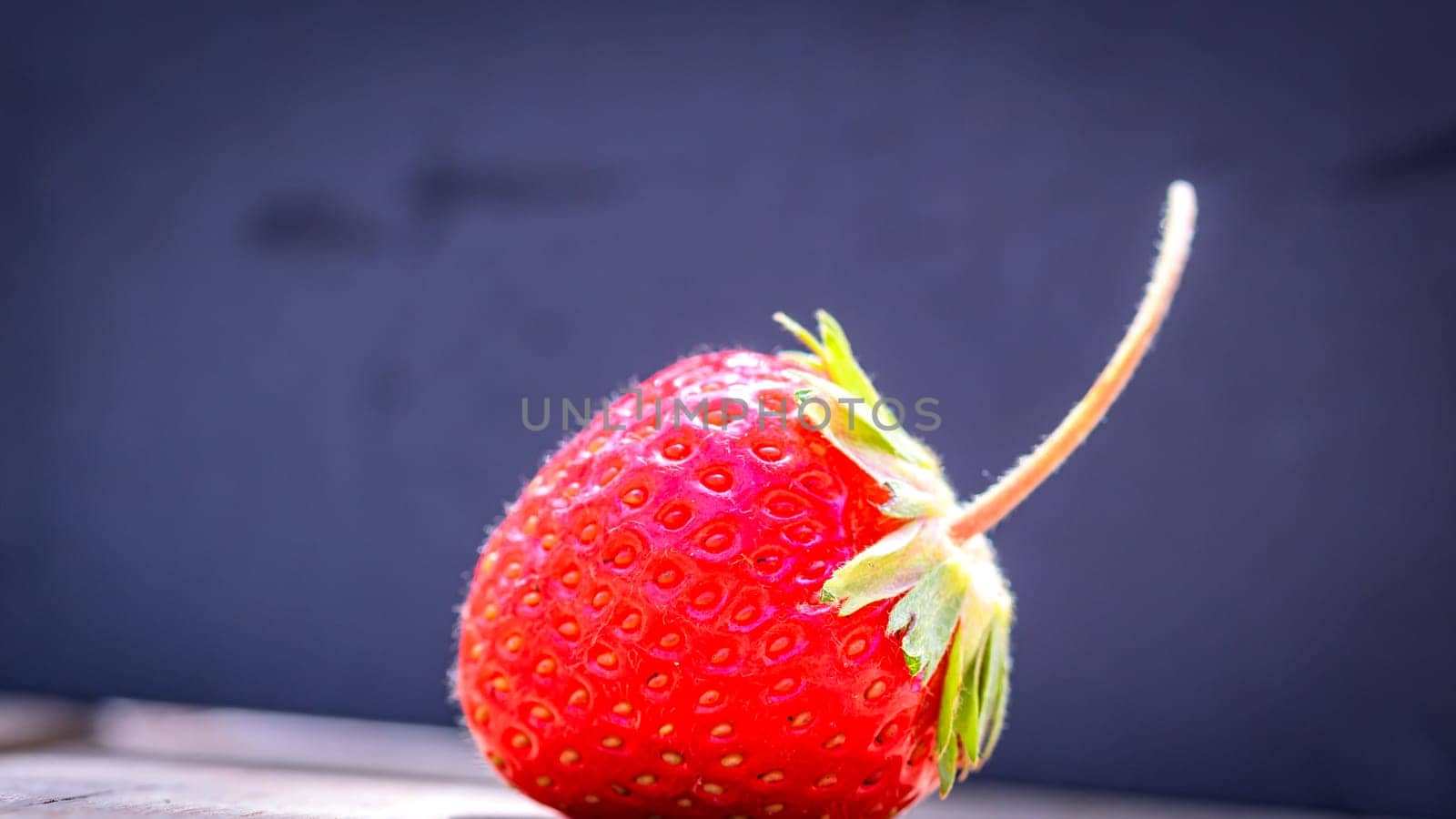 Close up of one strawberry on wooden board isolated on black background