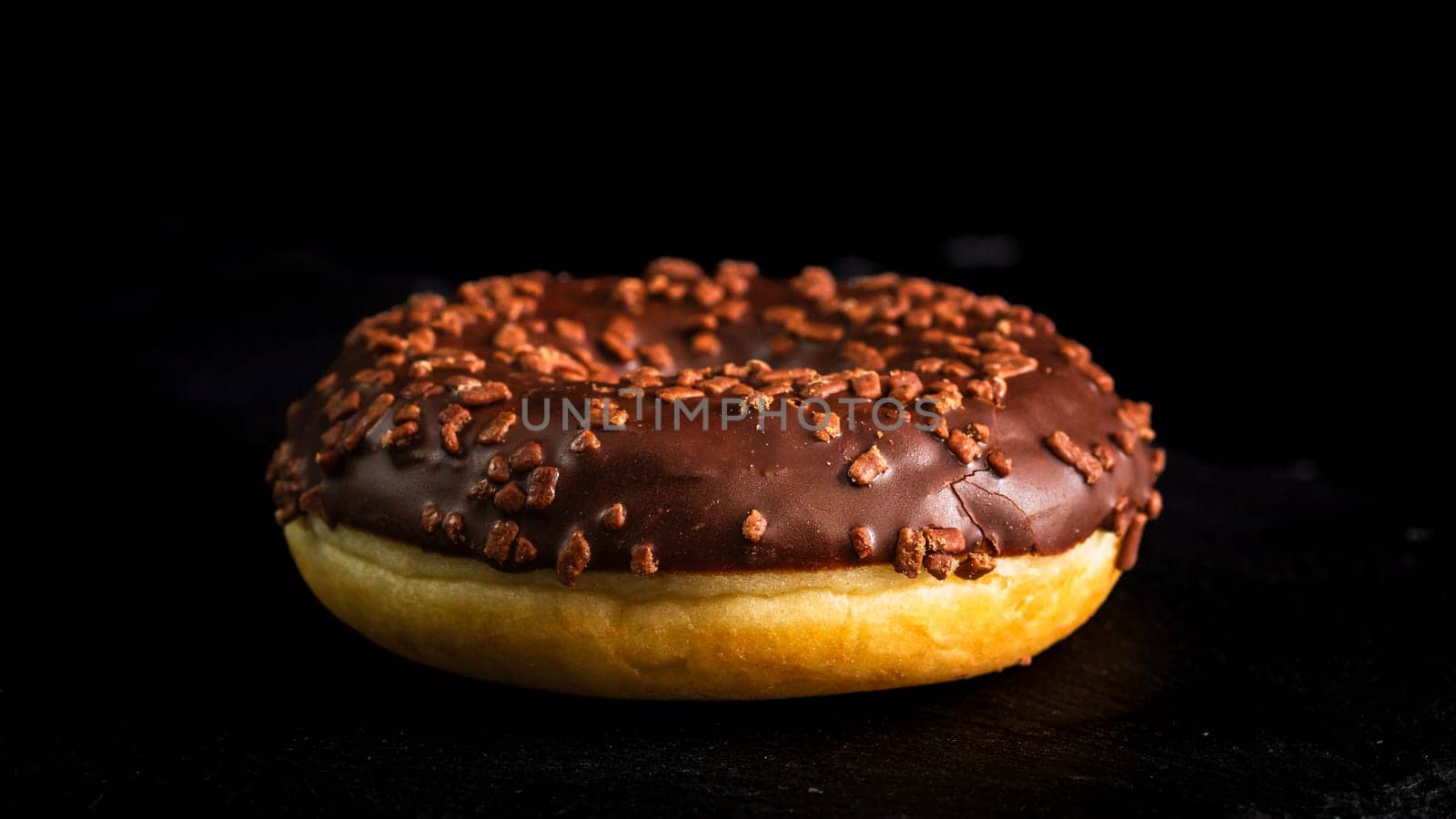 Chocolate glazed donut with chocolate chips isolated. Close up of delicious donut.