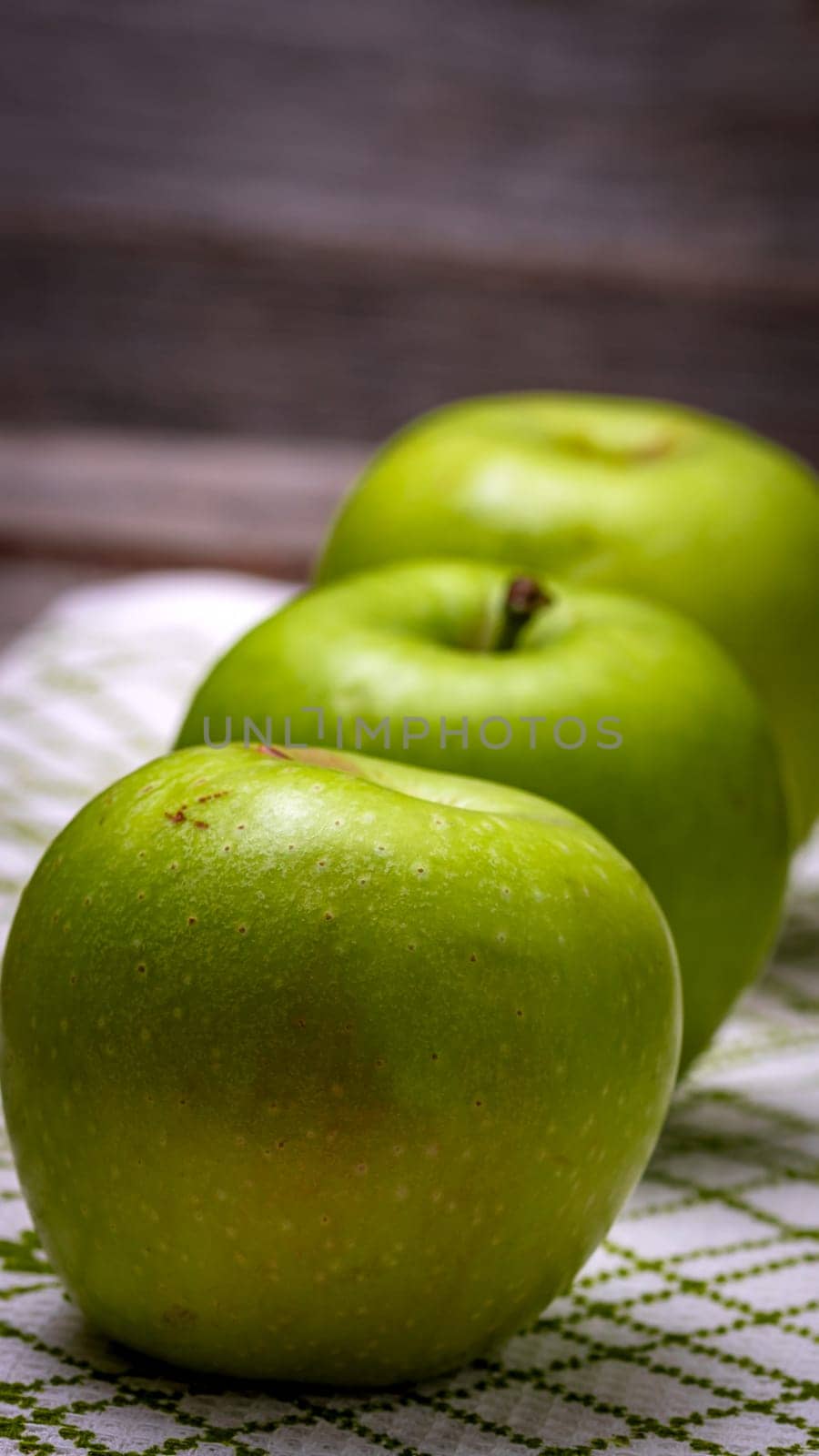 Detail on ripe green apples on wooden table.