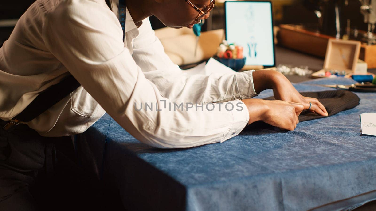 Seamstress preparing fabric on table by DCStudio