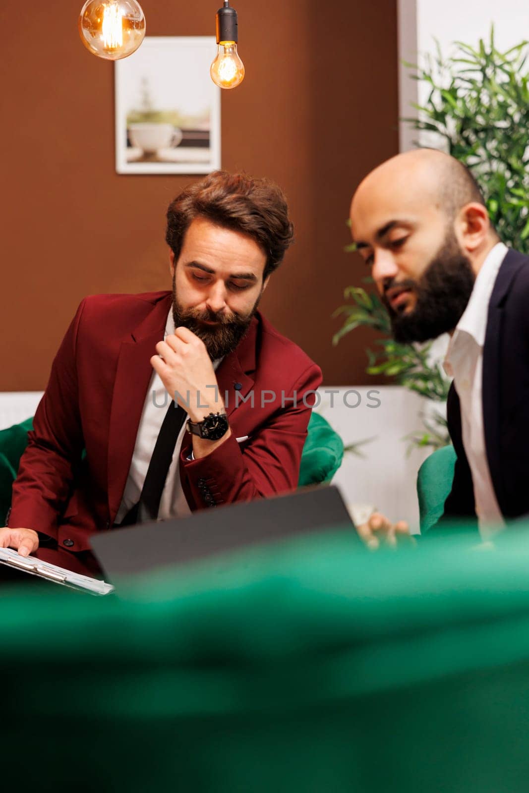 Employees in suits meet at hotel, discussing about new international partnership and sharing strategy ideas for common growth. Businessmen reviewing notes for conference with executive board.