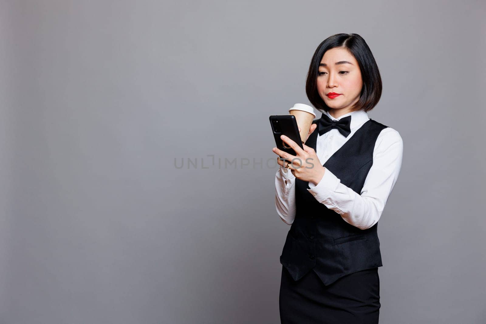 Waitress holding coffee and smartphone by DCStudio