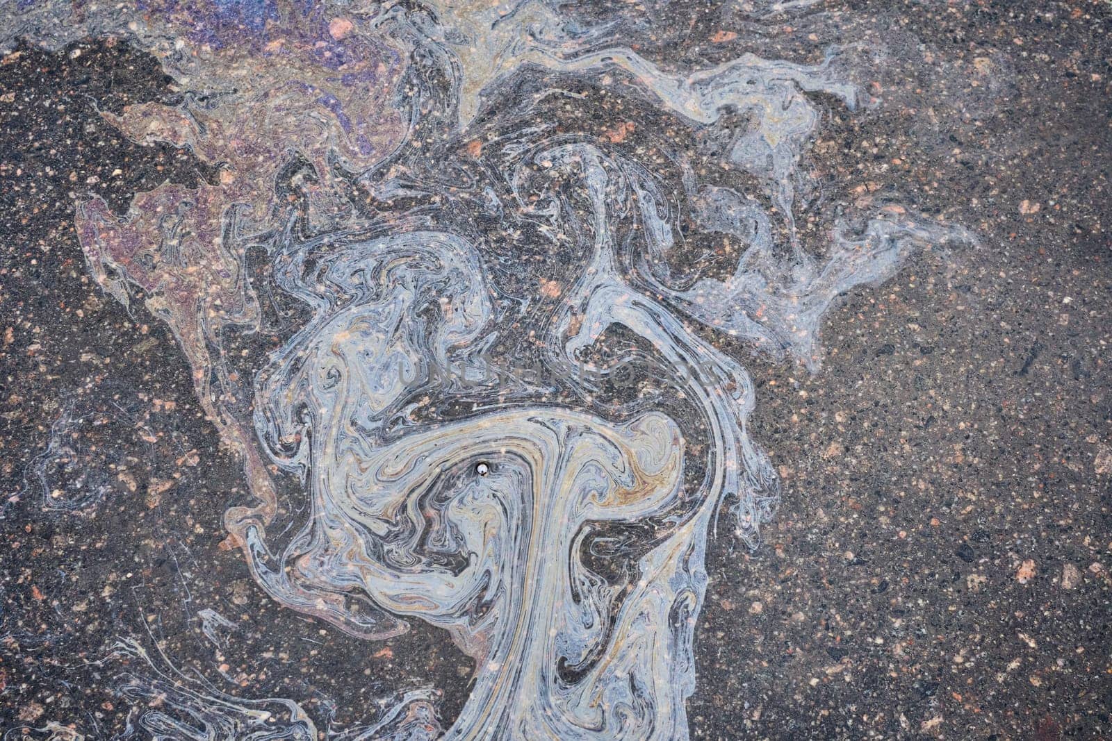 Colored oil stains close-up, color of a gasoline stain on asphalt as a texture or background.