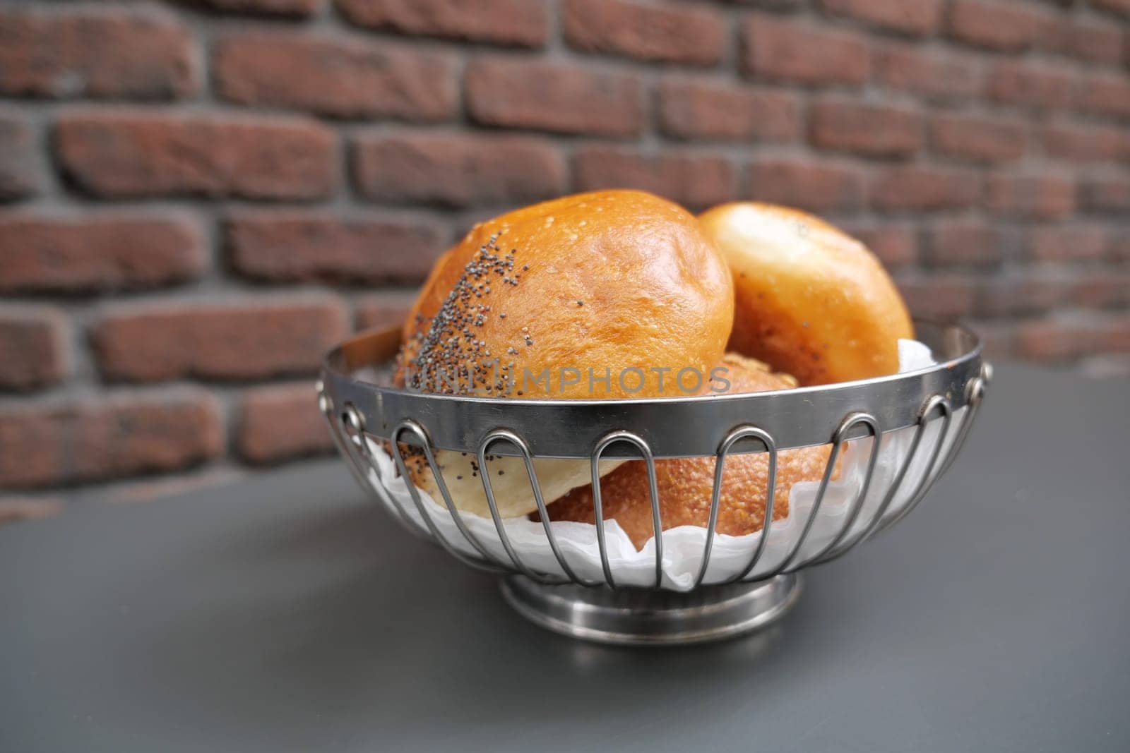 bread rolls rest in a black bowl on the table.