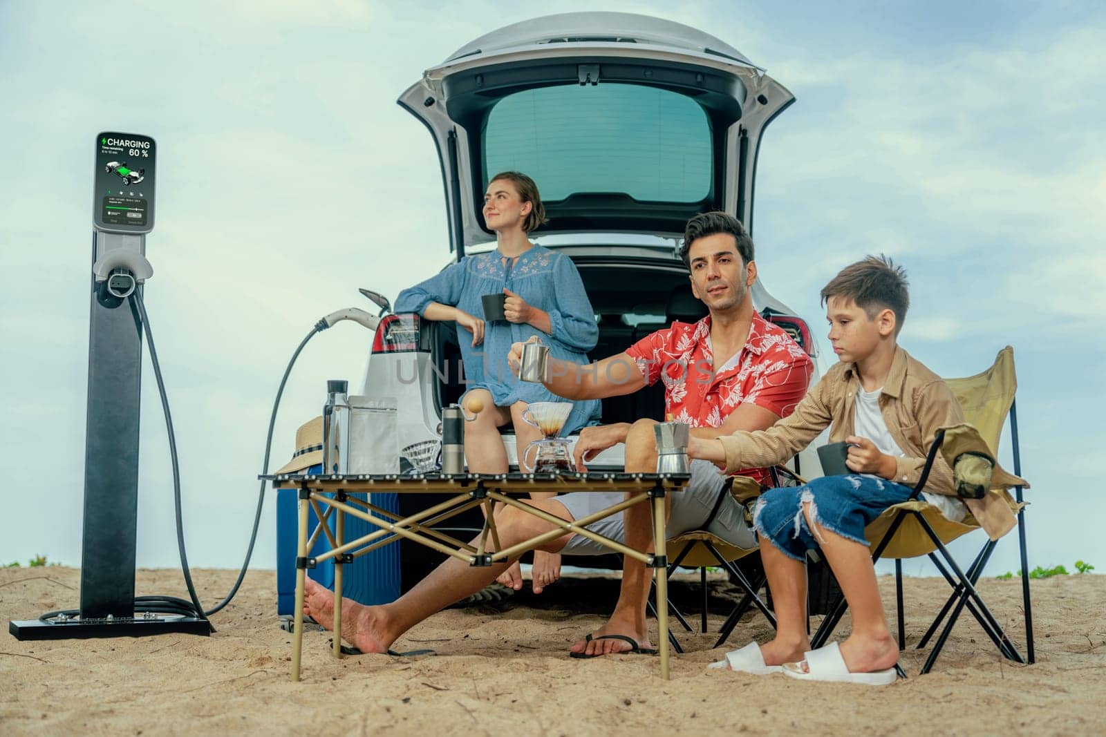 Family vacation trip traveling by the beach with electric car, happy family recharge EV car, enjoying outdoor camping coffee. Seascape travel and eco-friendly car for clean environment. Perpetual