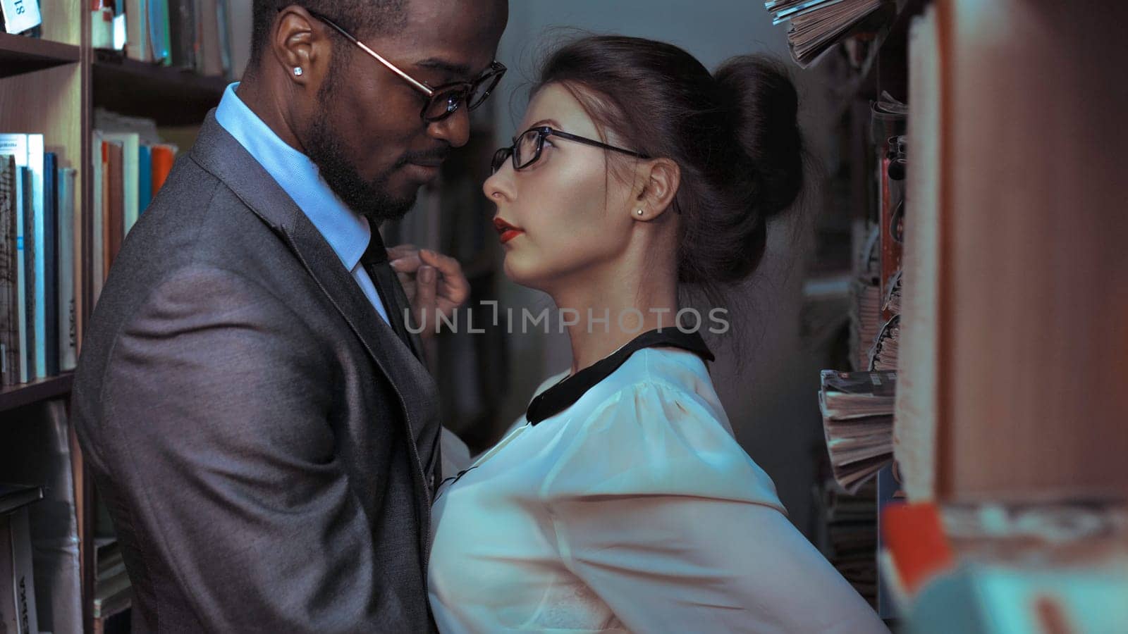 A black man and a white sexy girl stand face to face in the library. The temptation and passion between students of interracial affiliation Yaremche, Bukovel, Ukraine - January 10, 2022 by malyshph
