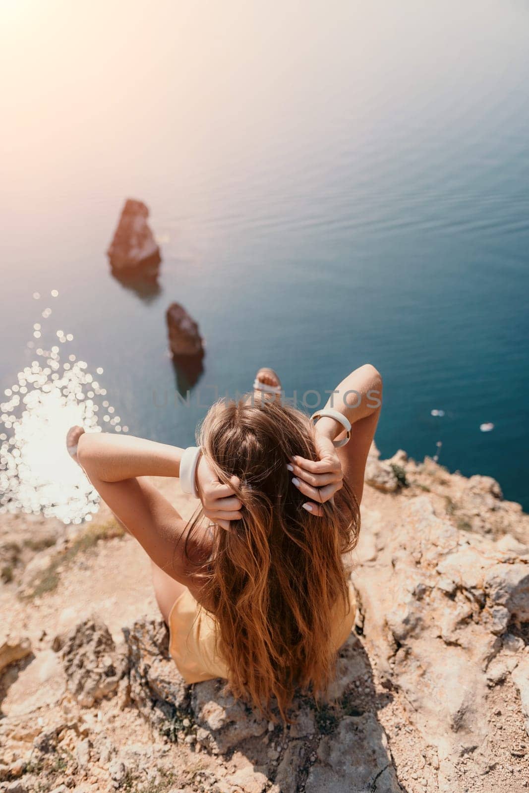 Woman travel sea. Happy tourist taking picture outdoors for memories. Woman traveler looks at the edge of the cliff on the sea bay of mountains, sharing travel adventure journey.