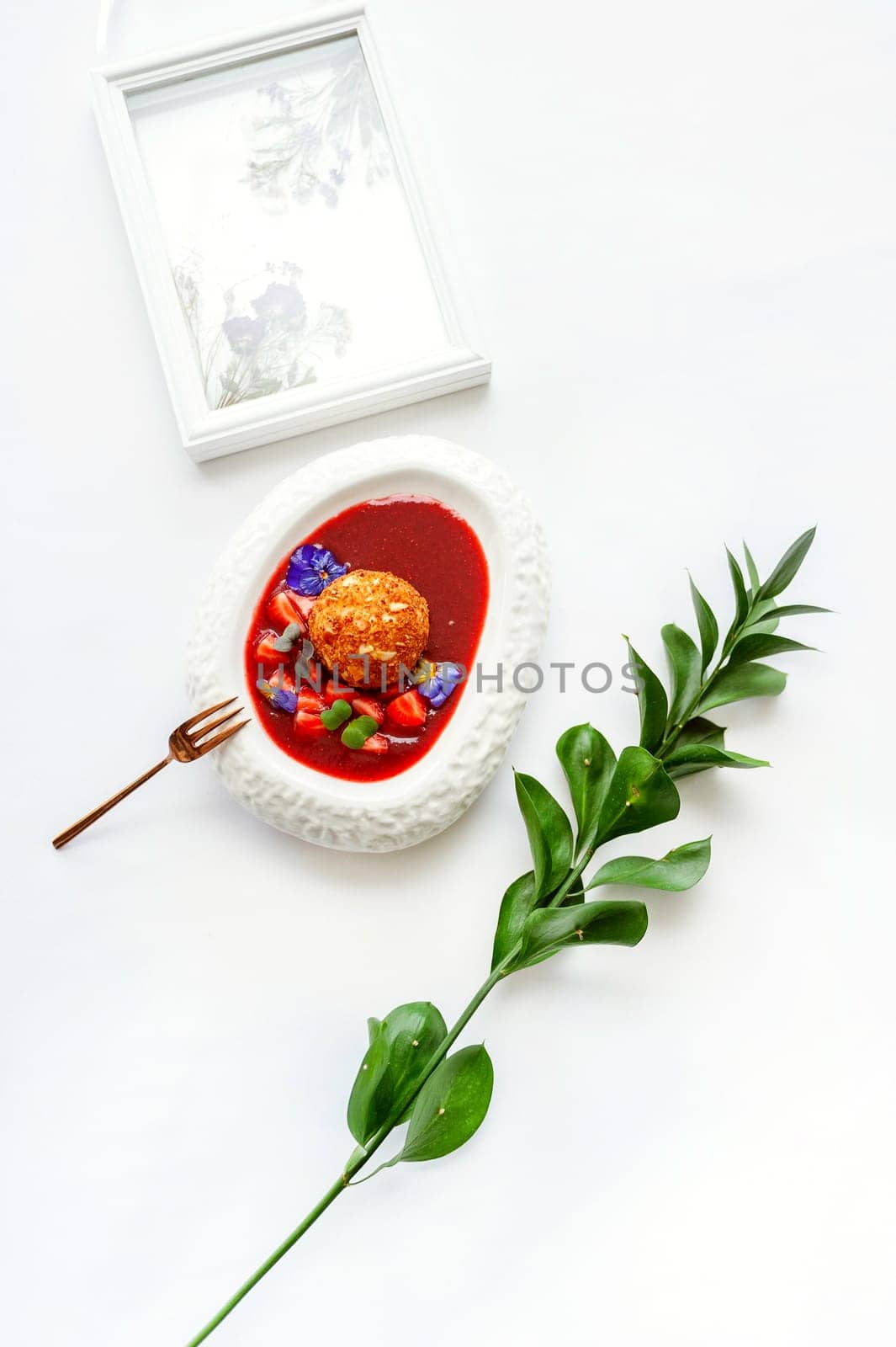 Dessert fried ice cream in strawberry sauce with berries. Top view with copy space on white table