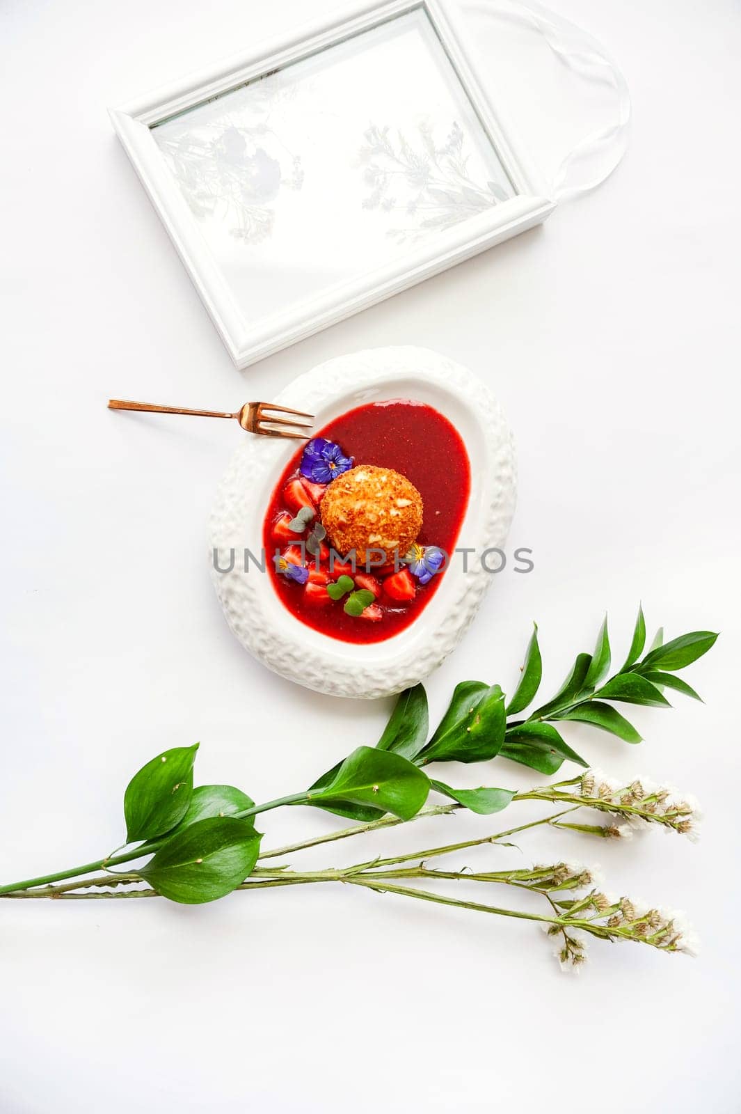 Dessert fried ice cream in strawberry sauce with berries. Top view with copy space on white table