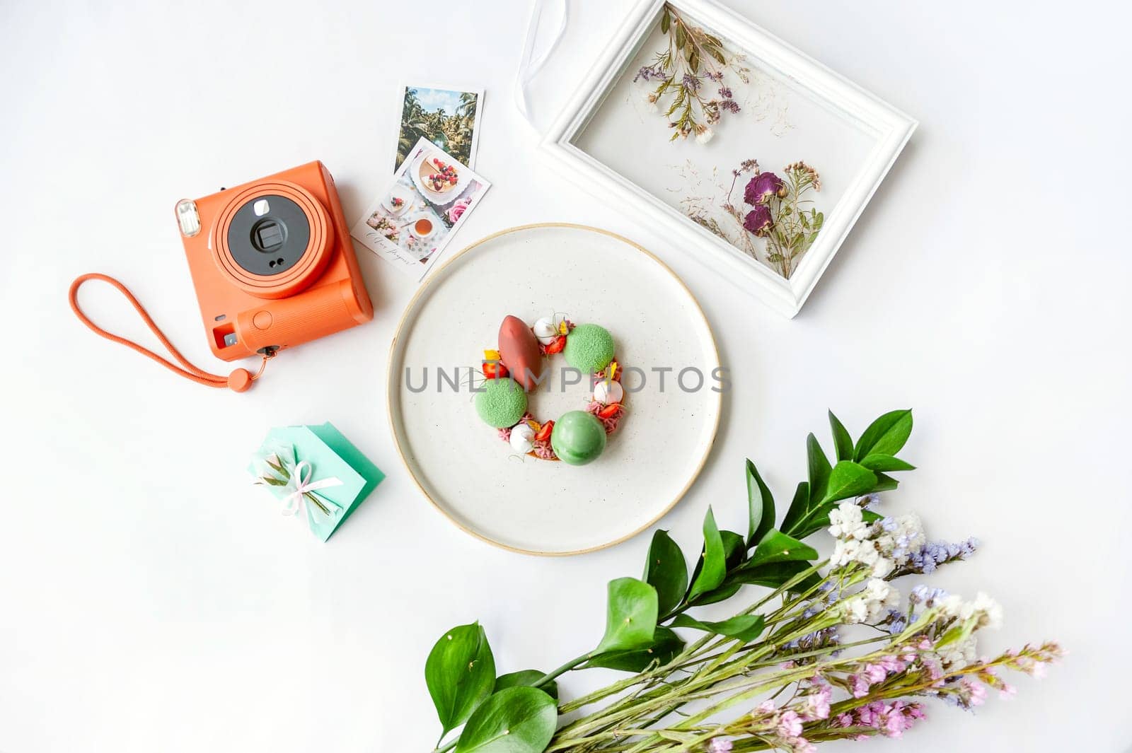 Beautiful background with dessert, polaroid camera and flowers. Top view on white table