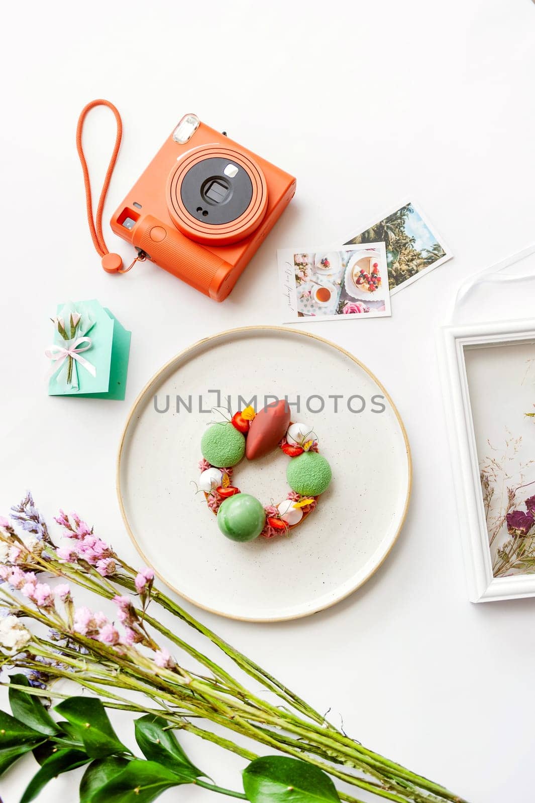 Beautiful background with dessert, polaroid camera and flowers. Top view on white table