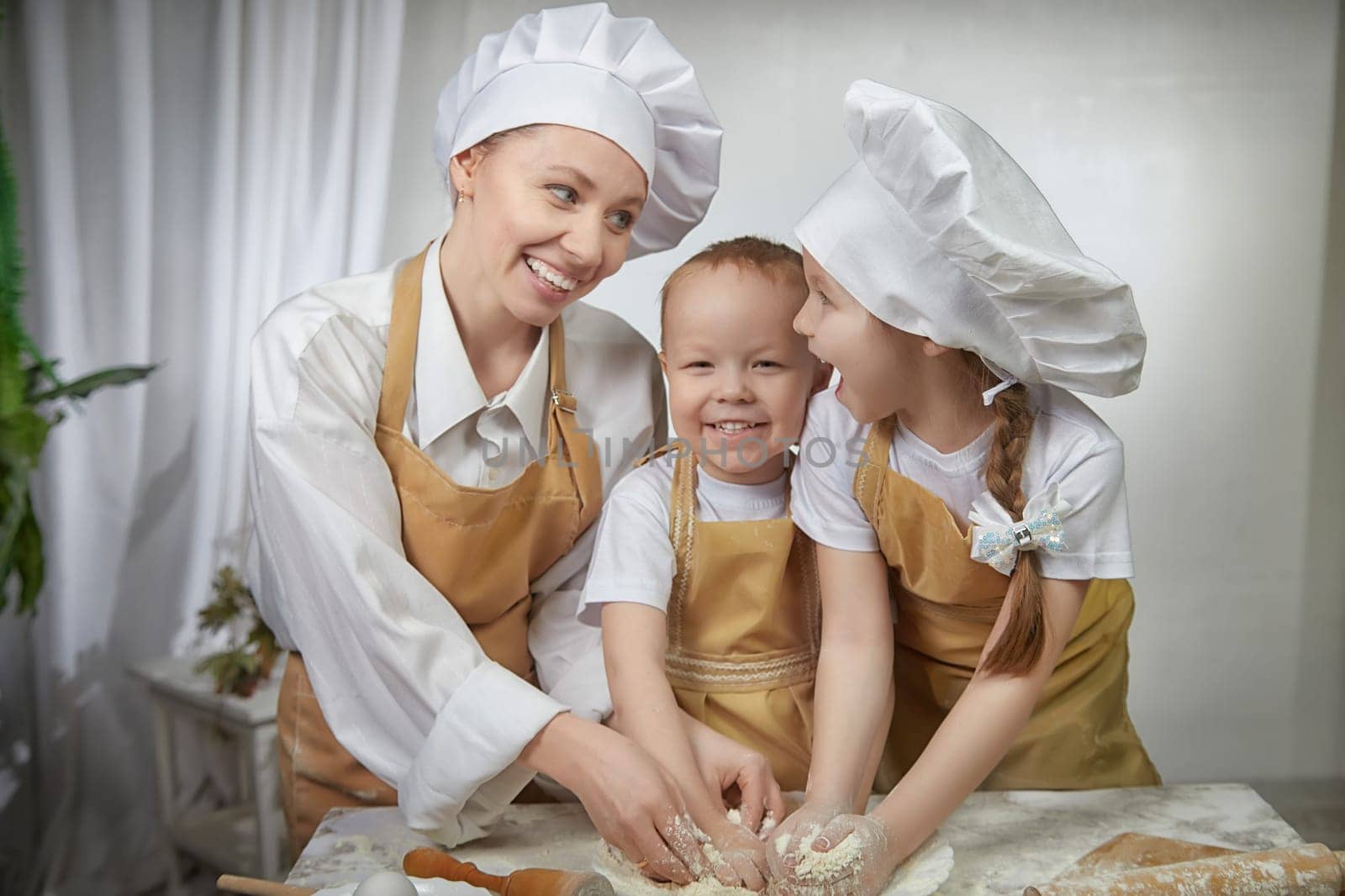 Cute oriental family with mother, daughter, son cooking in kitchen on Ramadan, Kurban-Bairam, Eid al-Adha. Funny family at a cook photo shoot. Pancakes, Maslenitsa, Easter
