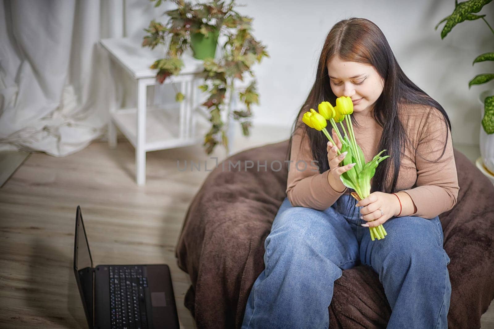 happy stylish fat plumb brunette girl with yellow tulips in room. happy young lady on International women's day. young hipster woman with present by keleny