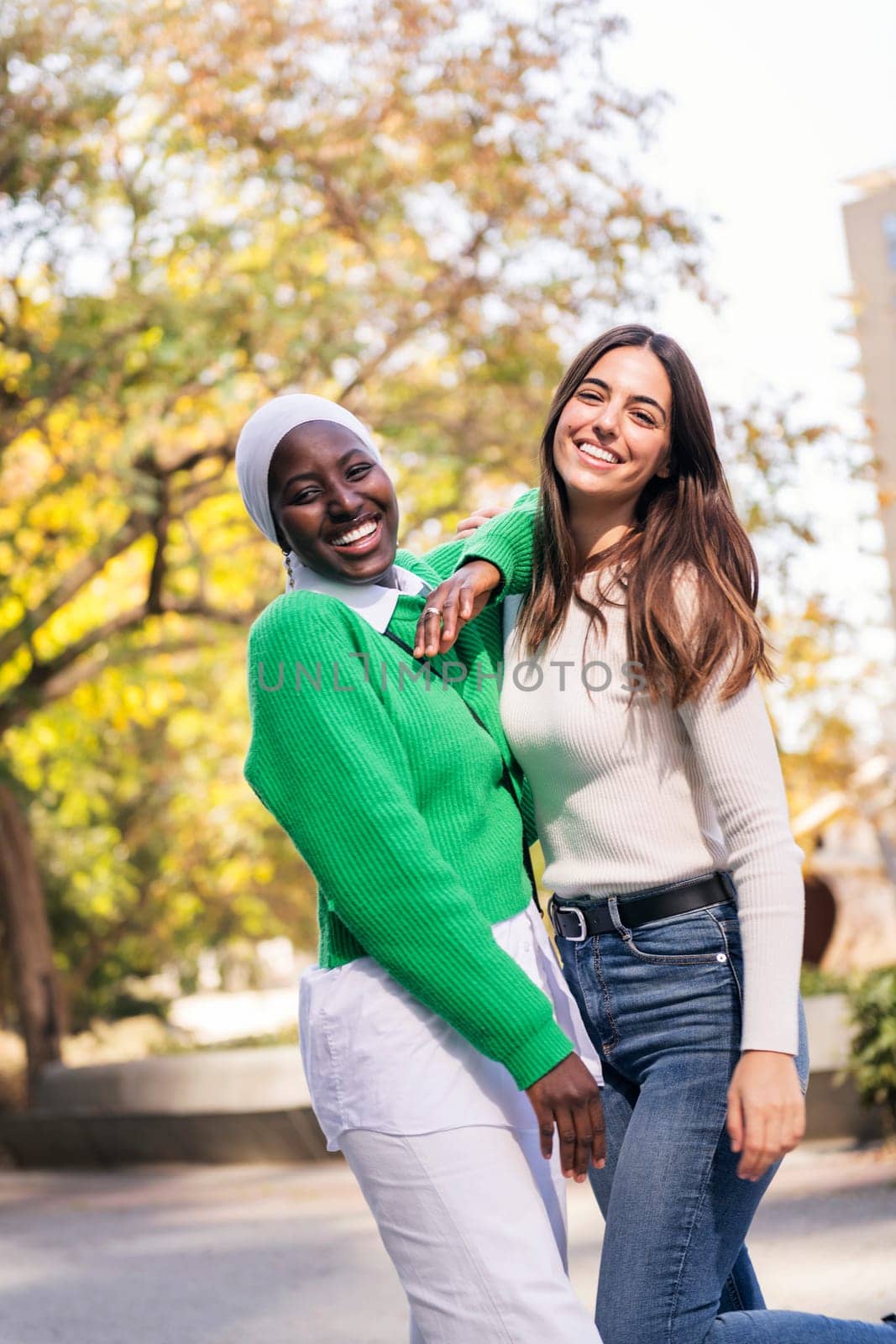 multiracial couple of two young women having fun looking at camera, concept of friendship and happiness, copy space for text