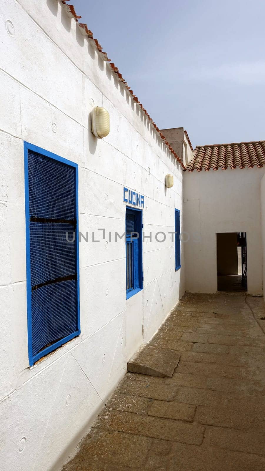 Asinara, Italy. August 11, 2021. A glimpse of the courtyard and the kitchen door of the prison museum. by Jamaladeen