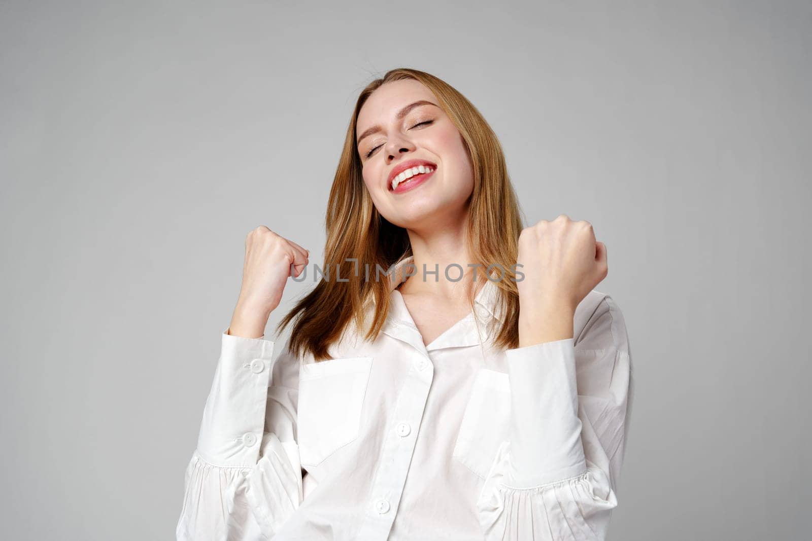 Jubilant Young Woman Celebrating a Victory With a Raised Fist in Studio by Fabrikasimf