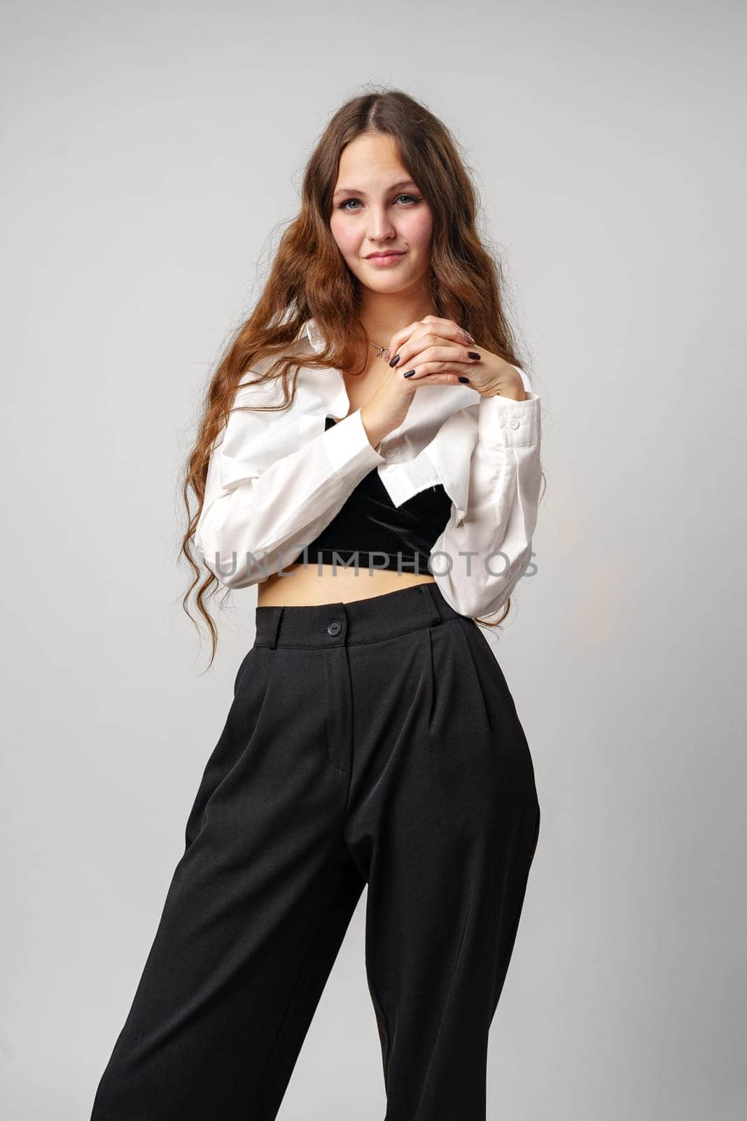 Confident Young Woman Posing in Casual Black and White Outfit Against Grey Background by Fabrikasimf