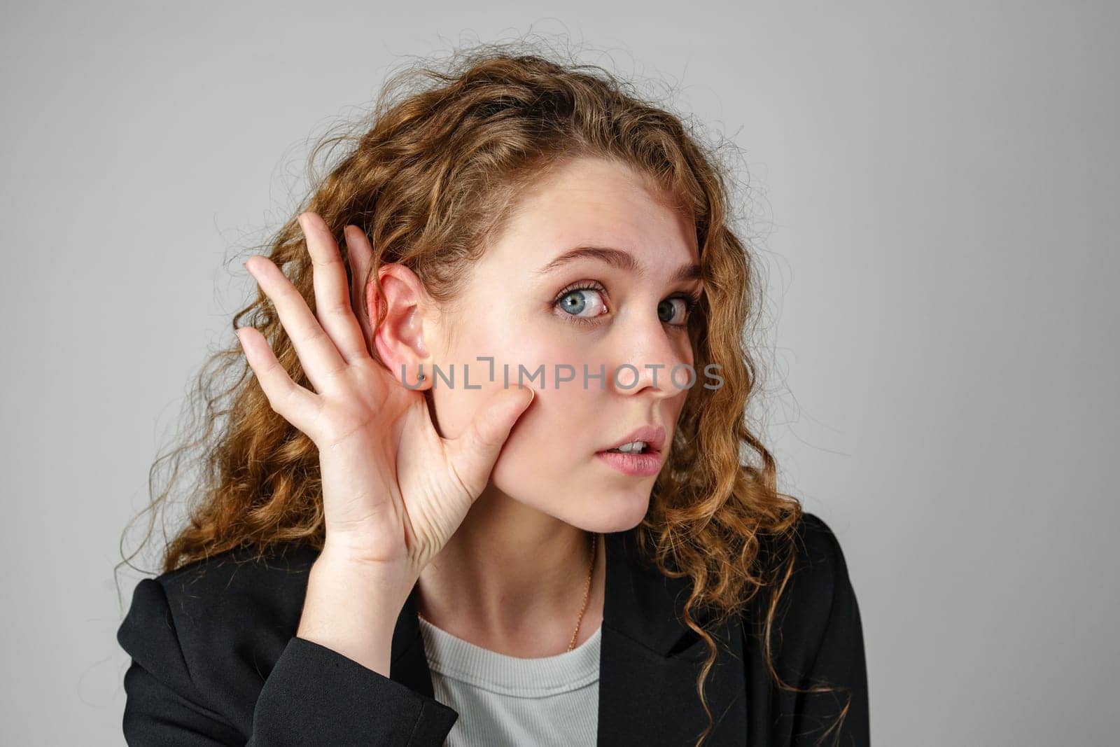 Young Woman Listening With Hand to Ear in Studio