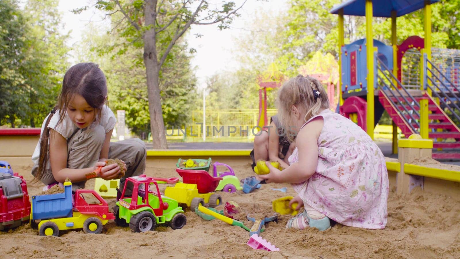 Two girls sitting in a sandbox and playing in the sand