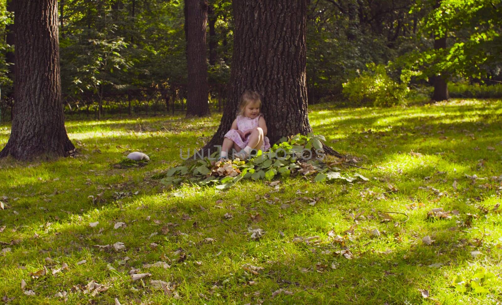A girl sitting near the tree in the park by Chudakov