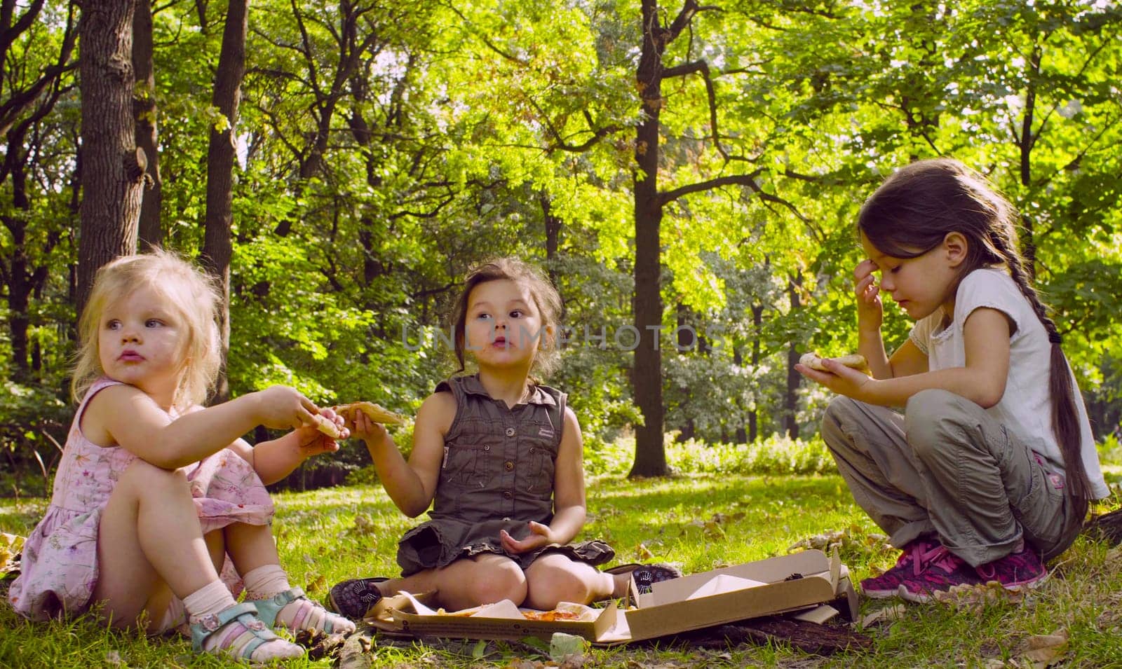 Breakfast on the grass. Three girls sitting in the park and eating pizza.