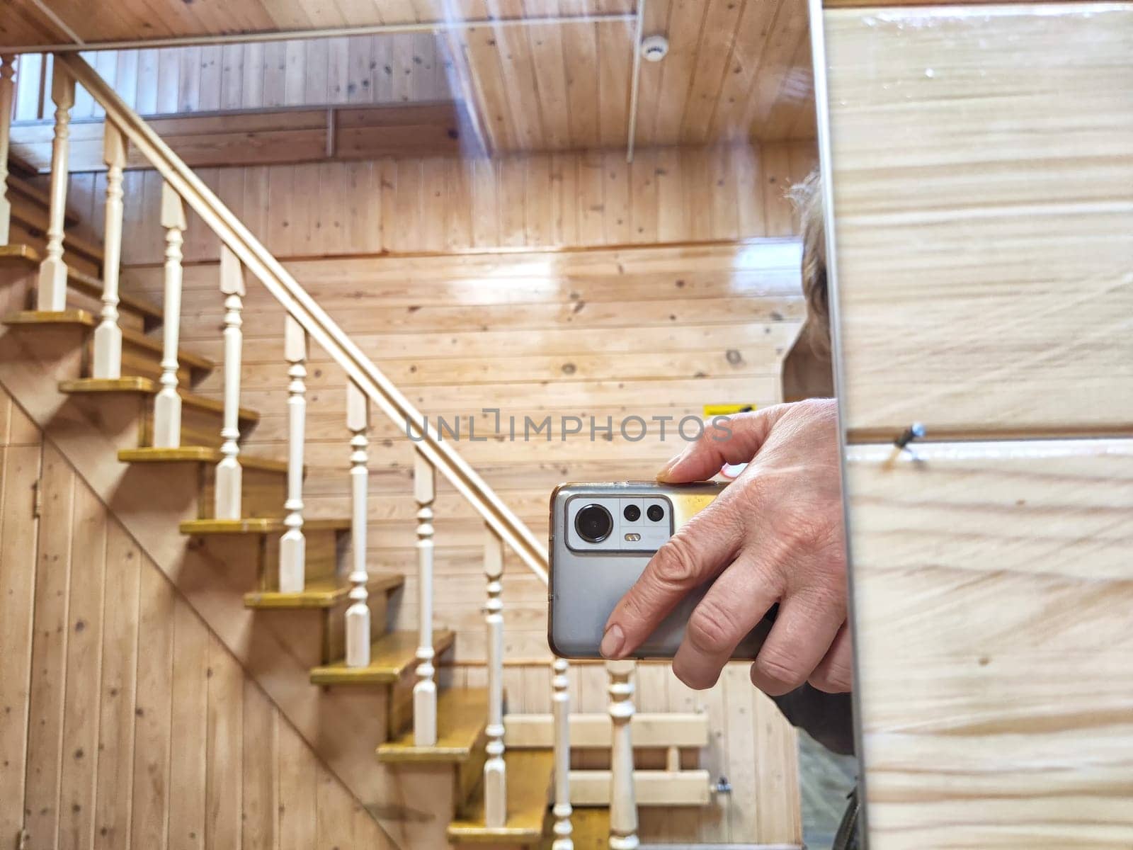 Close-up of a hand holding a phone to take a reflection selfie in mirror. Person Capturing Reflection in Mirror With Smartphone in Wooden Interior
