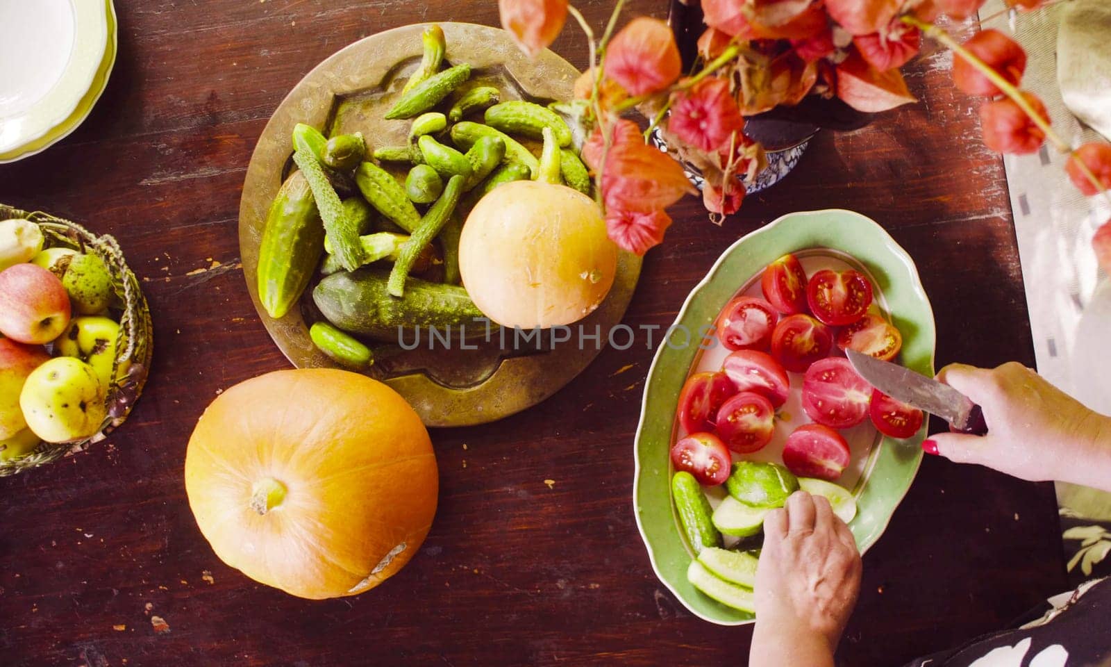 Senior female hands cutting tomatoes and cucumbers by Chudakov