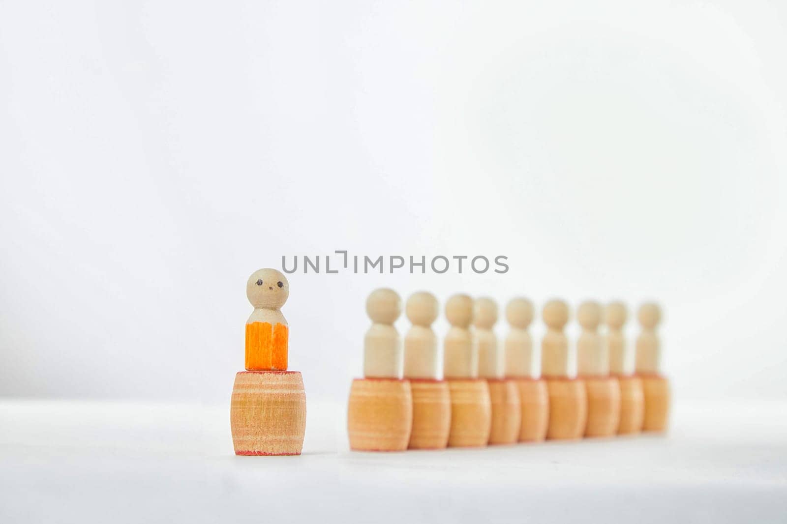 Wooden figurines with a leader and group with partial focus. The concept of distinguishing a leader from the crowd. Sighted, intelligent, different among the blind group