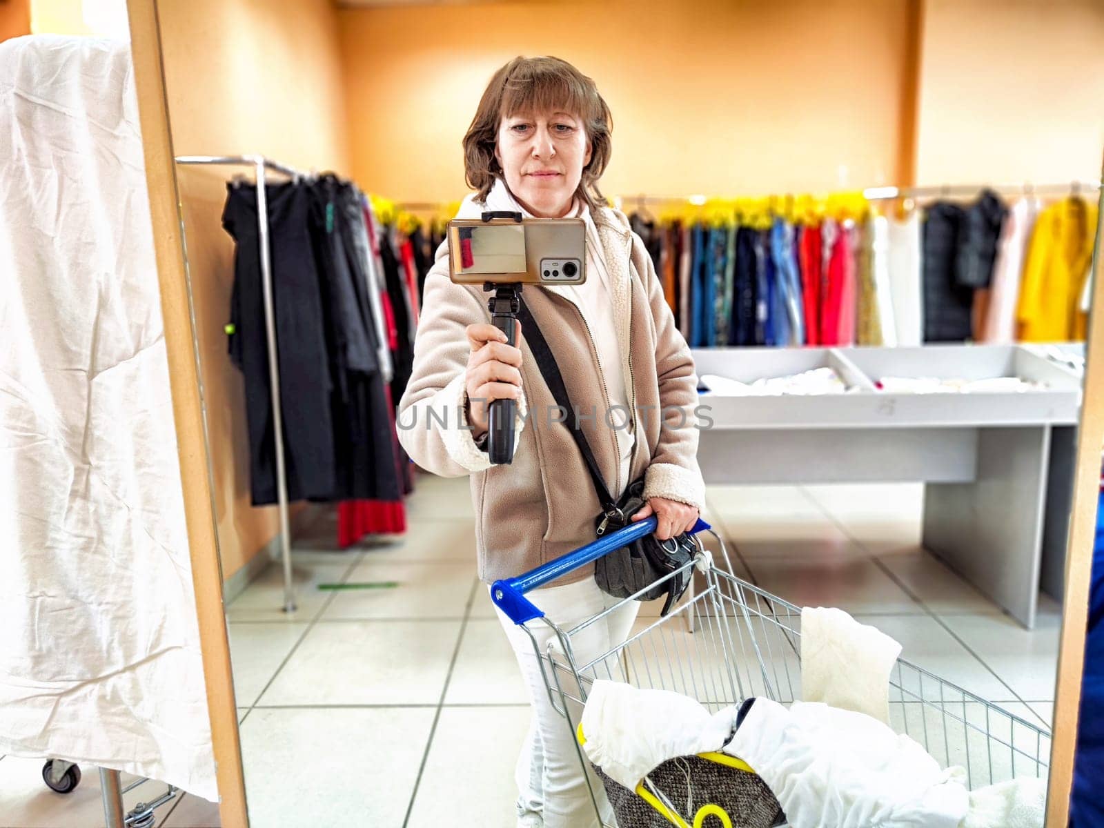 A girl while shopping in a store. A middle-aged woman takes a selfie in the mirror in the trading floor by keleny