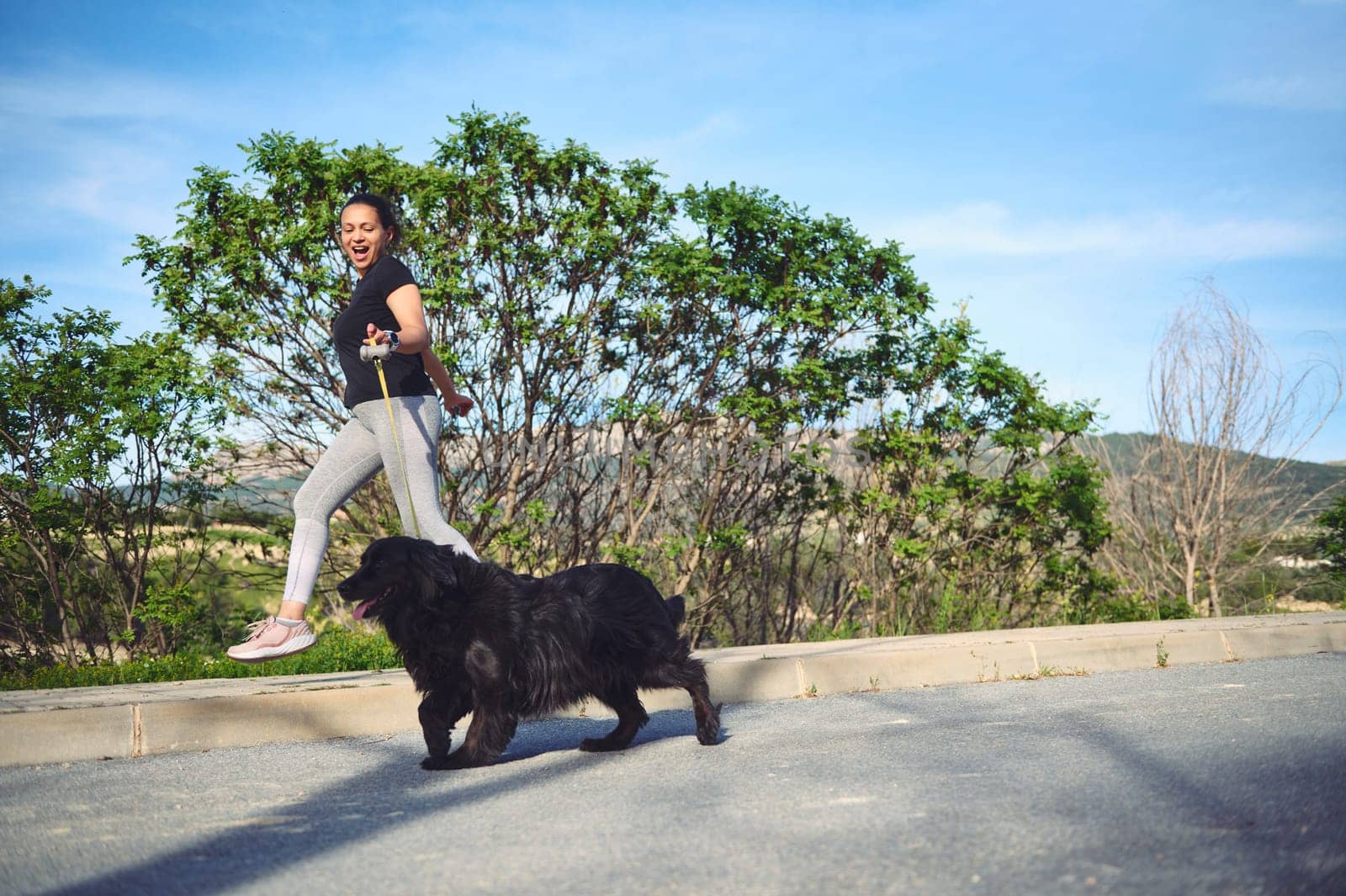 I'm jogging with my pet outdoors. Cheerful happy woman enjoying her morning run with her cocker spaniel dog being walked on leash on the nature. People. Playing pets. Healthy active lifestyle concept.