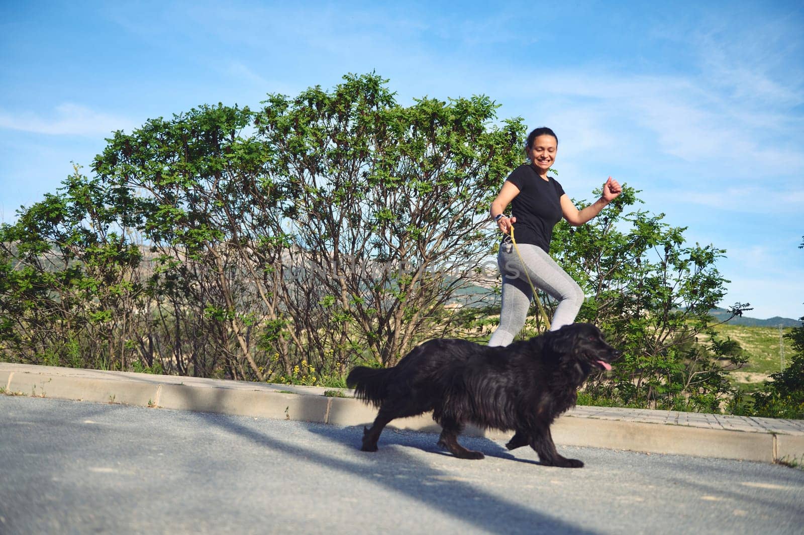 Full length portrait of young active woman running and walking her dog on leash on the nature outdoors. People. Playing pets. Sport. Active and healthy lifestyle concept by artgf