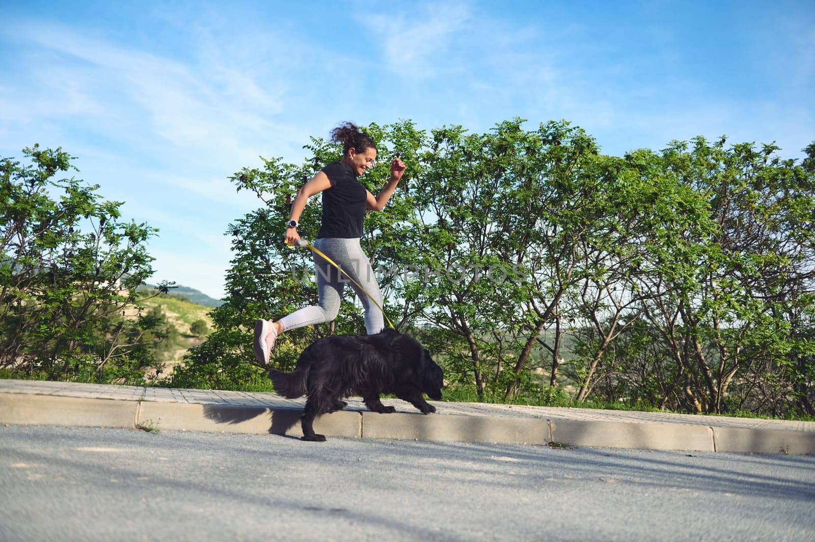 Sporty active woman running with her dog on leash in mountains nature. People. Playing pets. Love for animals and nature concept by artgf