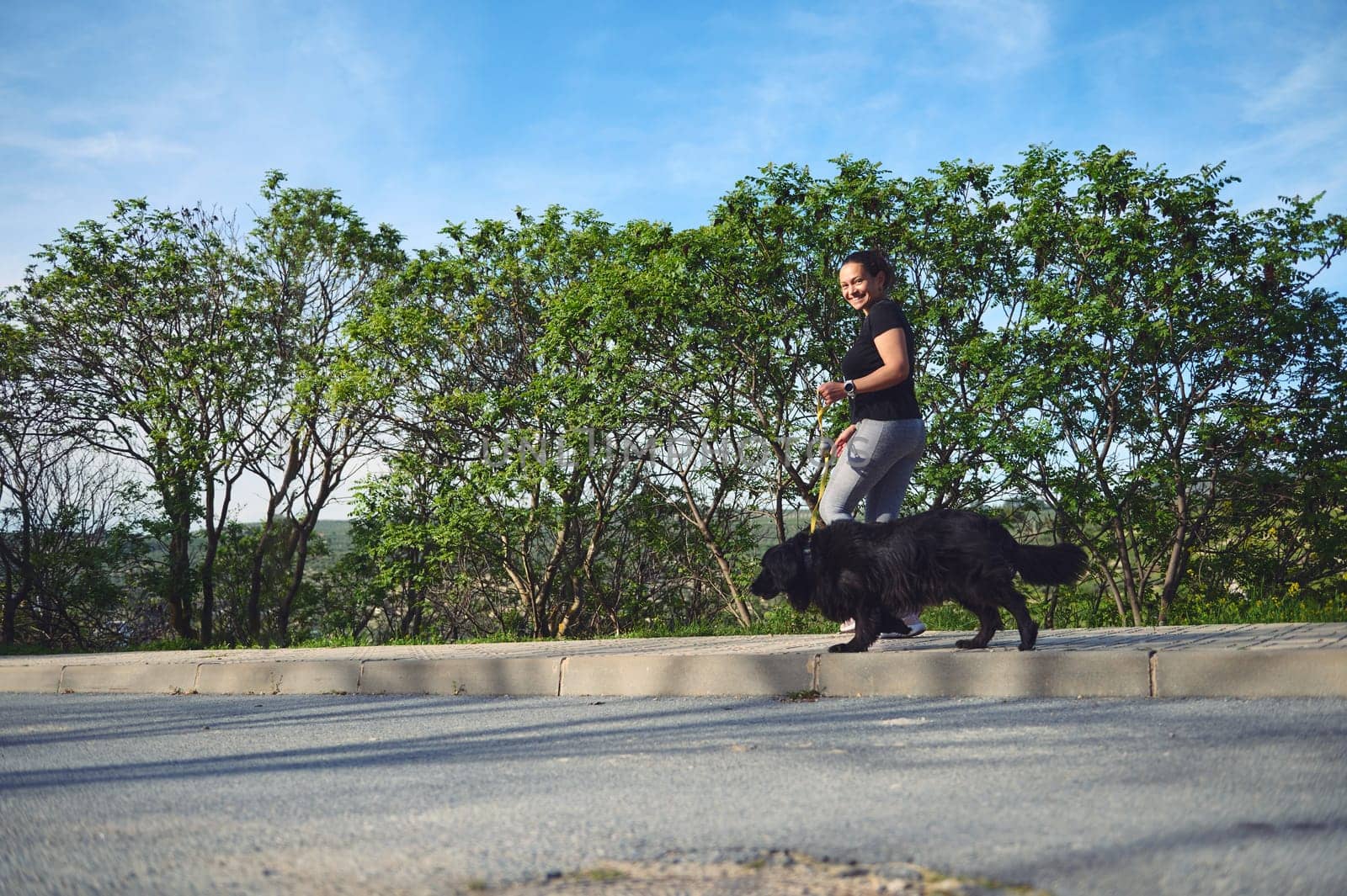 Sporty active woman running with her dog on leash in mountains nature. People. Playing pets. Love for animals and nature concept