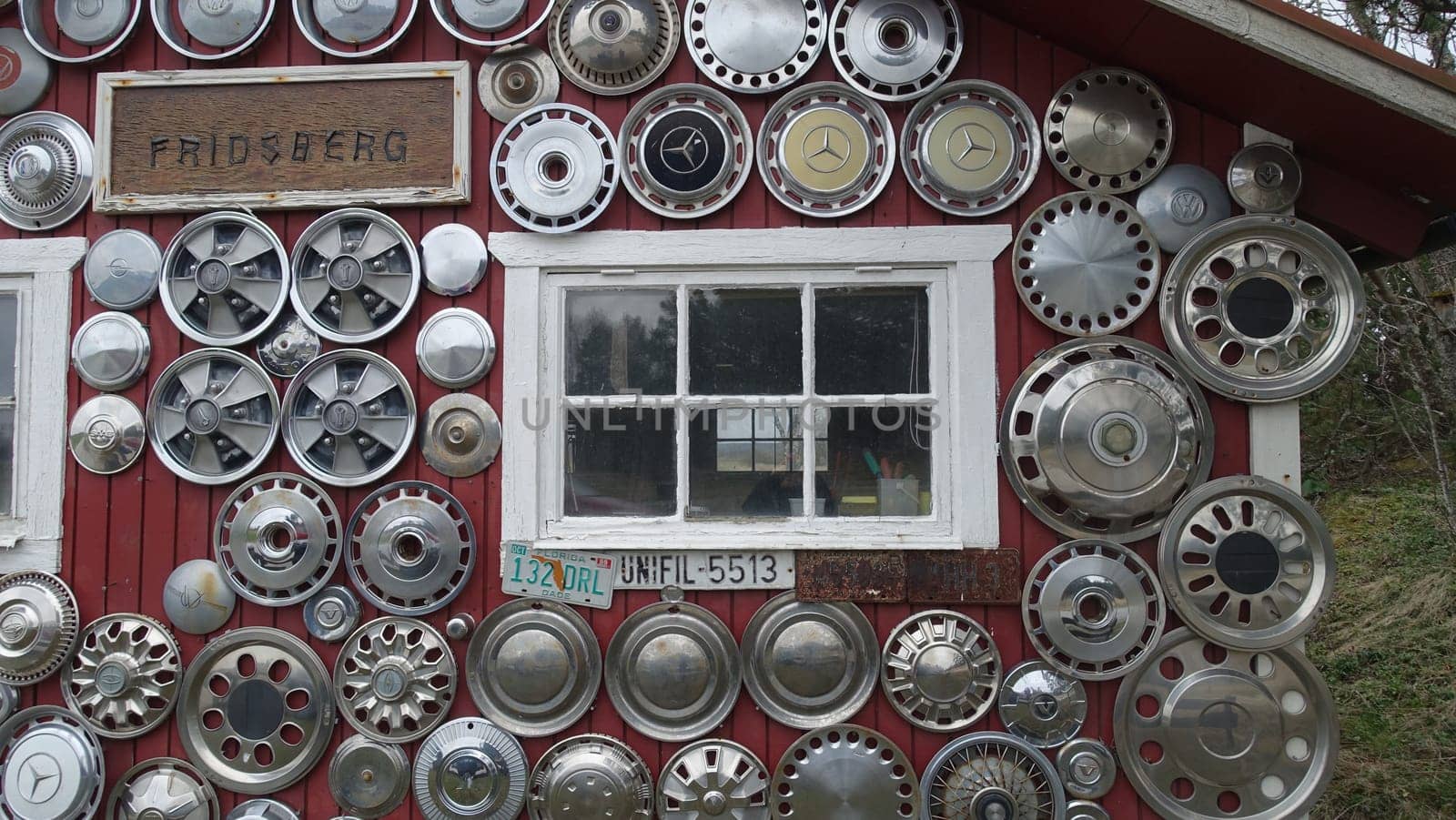Sweden, April 21, 2024. The facade of a house dotted with antique car rims. View from the street during a cloudy day.