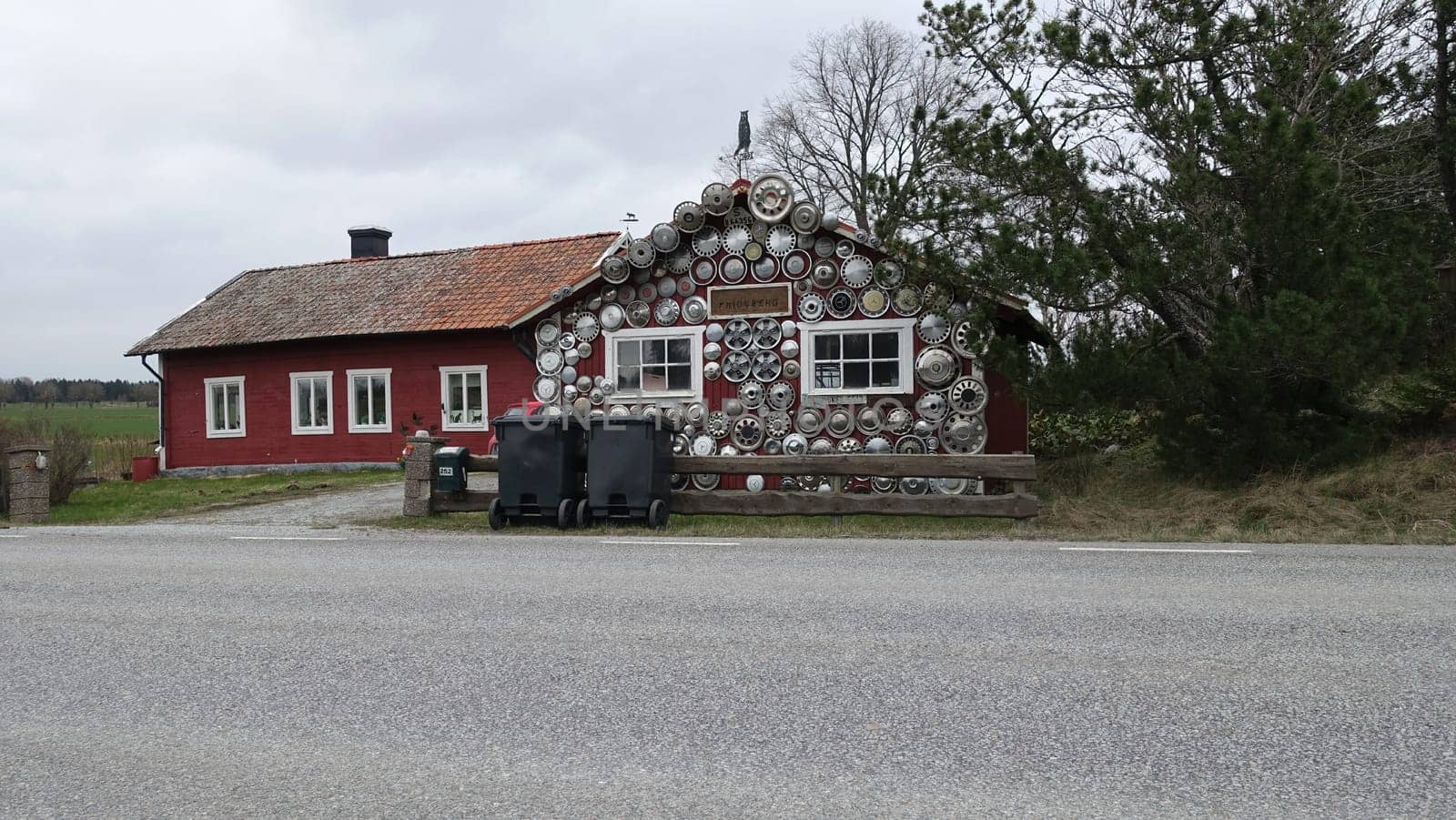 Sweden, April 21, 2024. The facade of a house dotted with antique car rims. by Jamaladeen