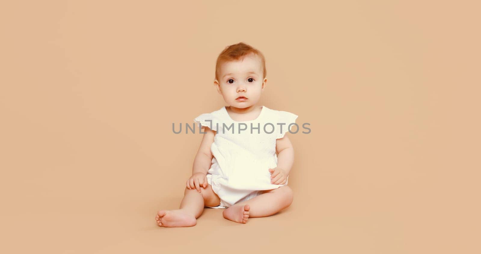 Portrait happy cute baby crawling on the floor on brown studio background by Rohappy
