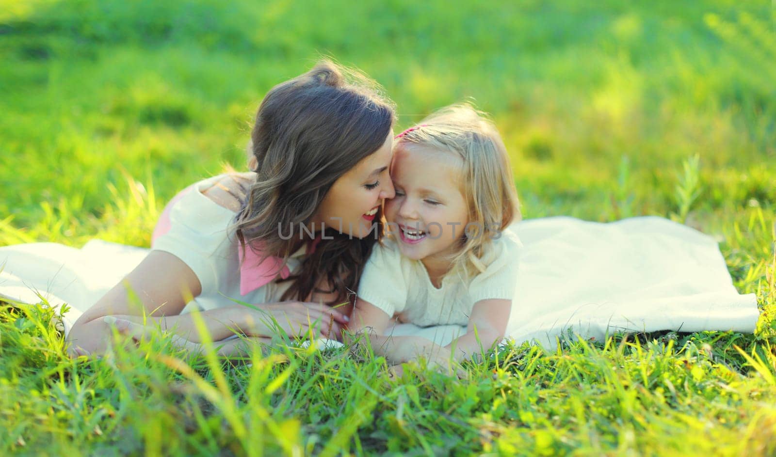 Happy cheerful smiling mother with little girl child daughter on the grass in sunny summer park by Rohappy